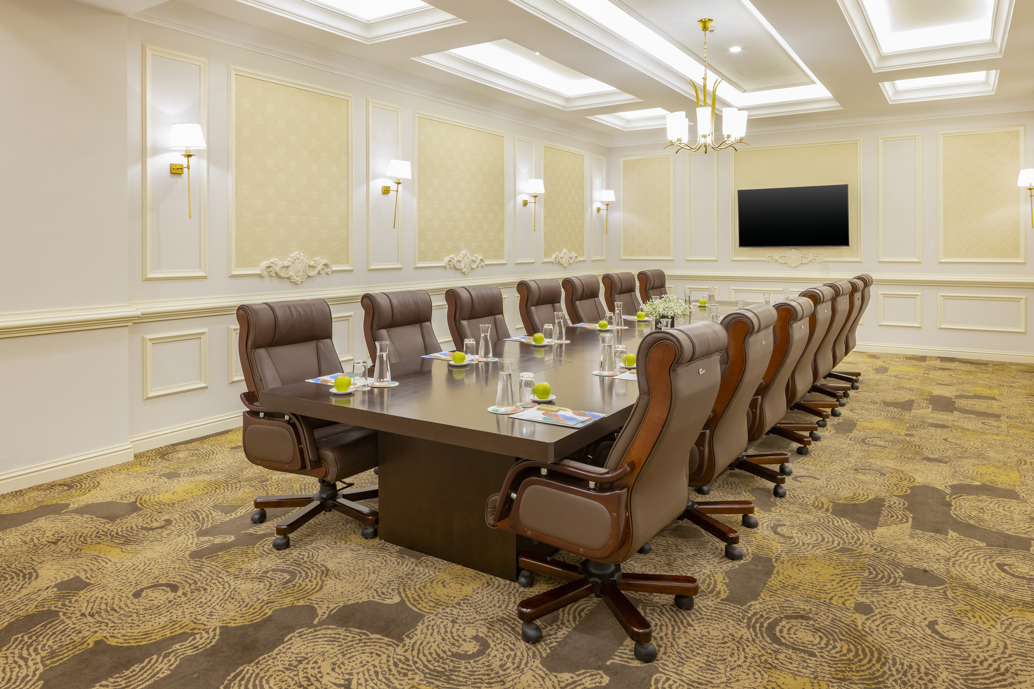 Luxury boardroom with executive table, brown leather chairs, and wall TV.