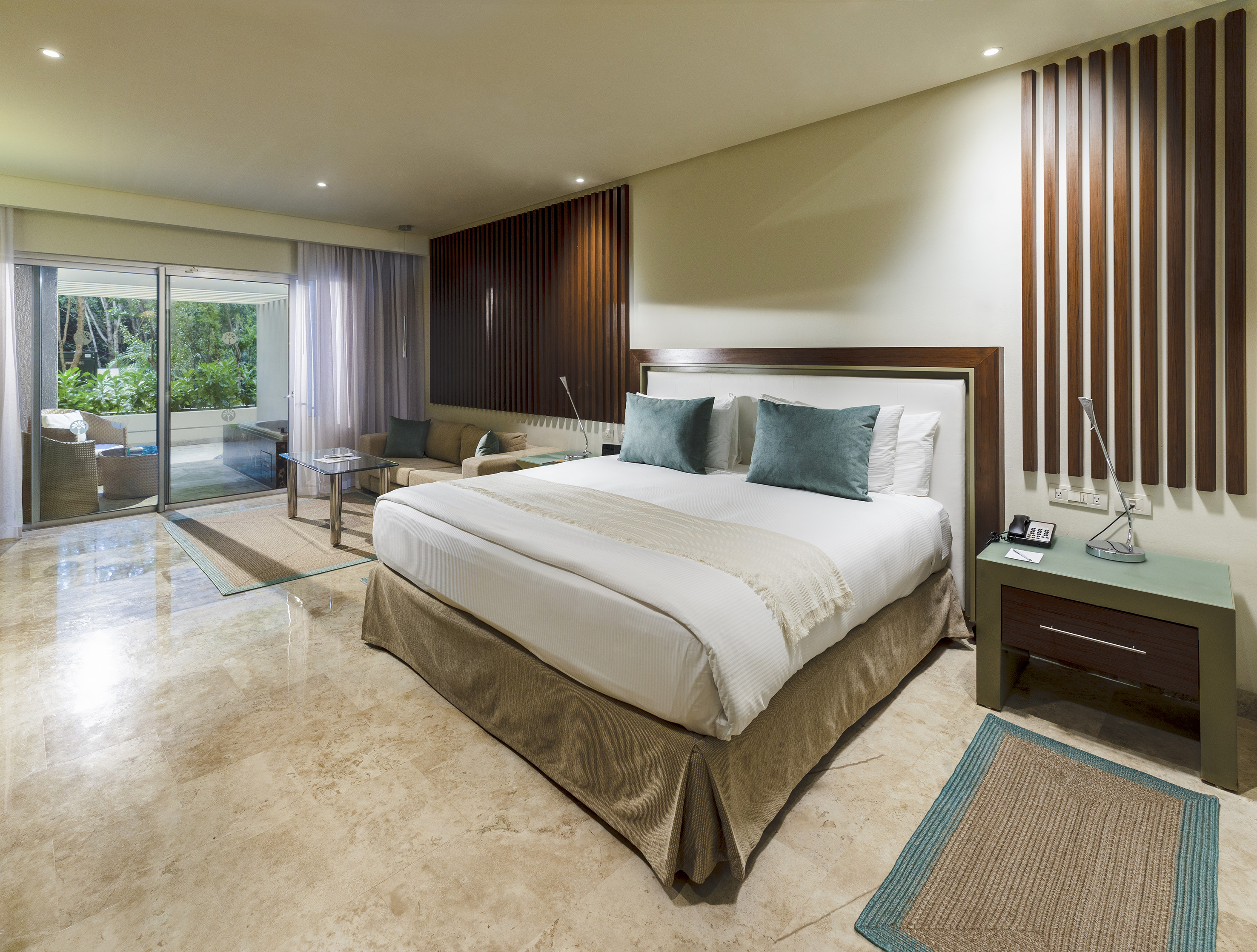 Modern luxury hotel suite, king bed, wood wall, patio garden view.