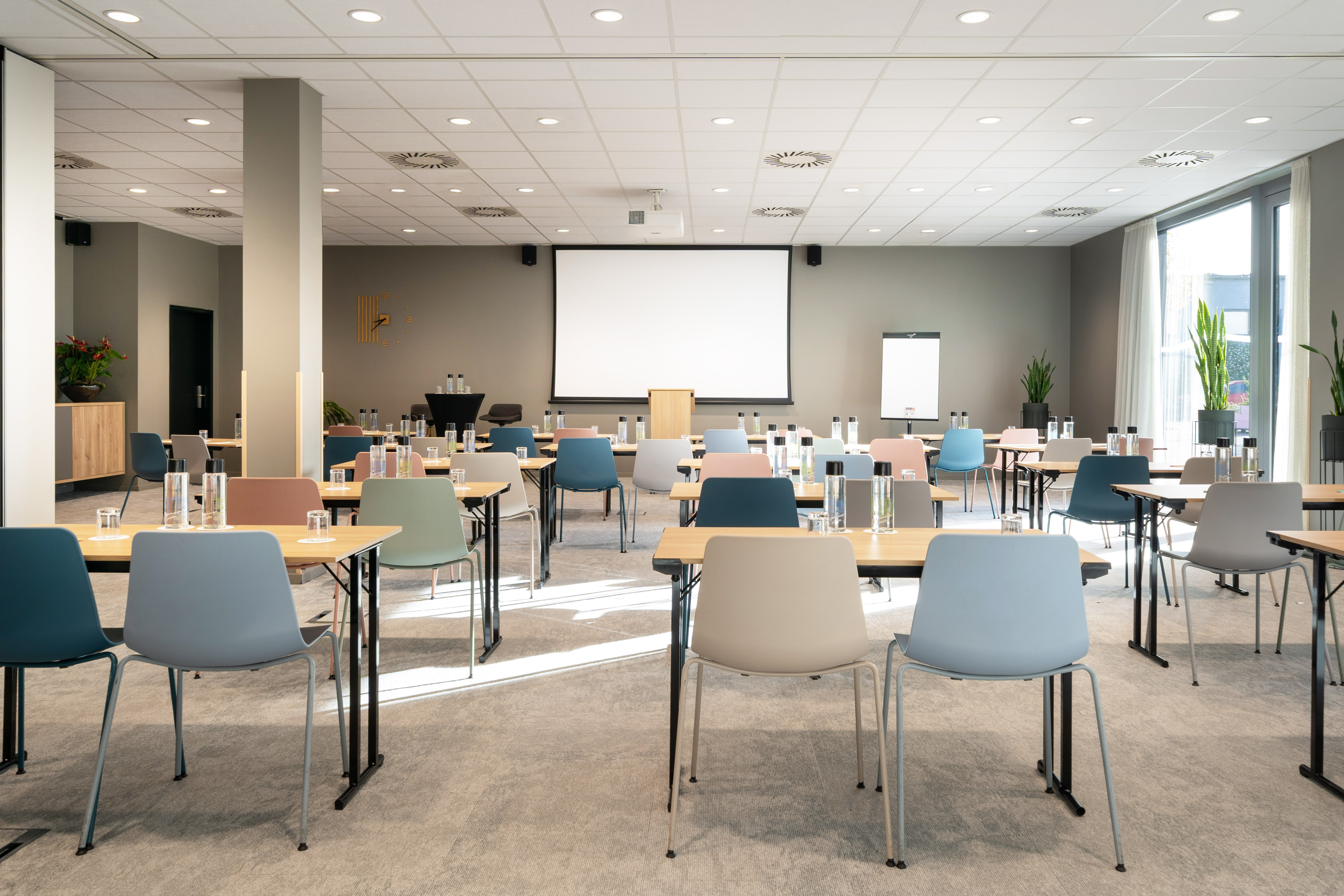 Modern meeting room setup with projector screen and colorful chairs.