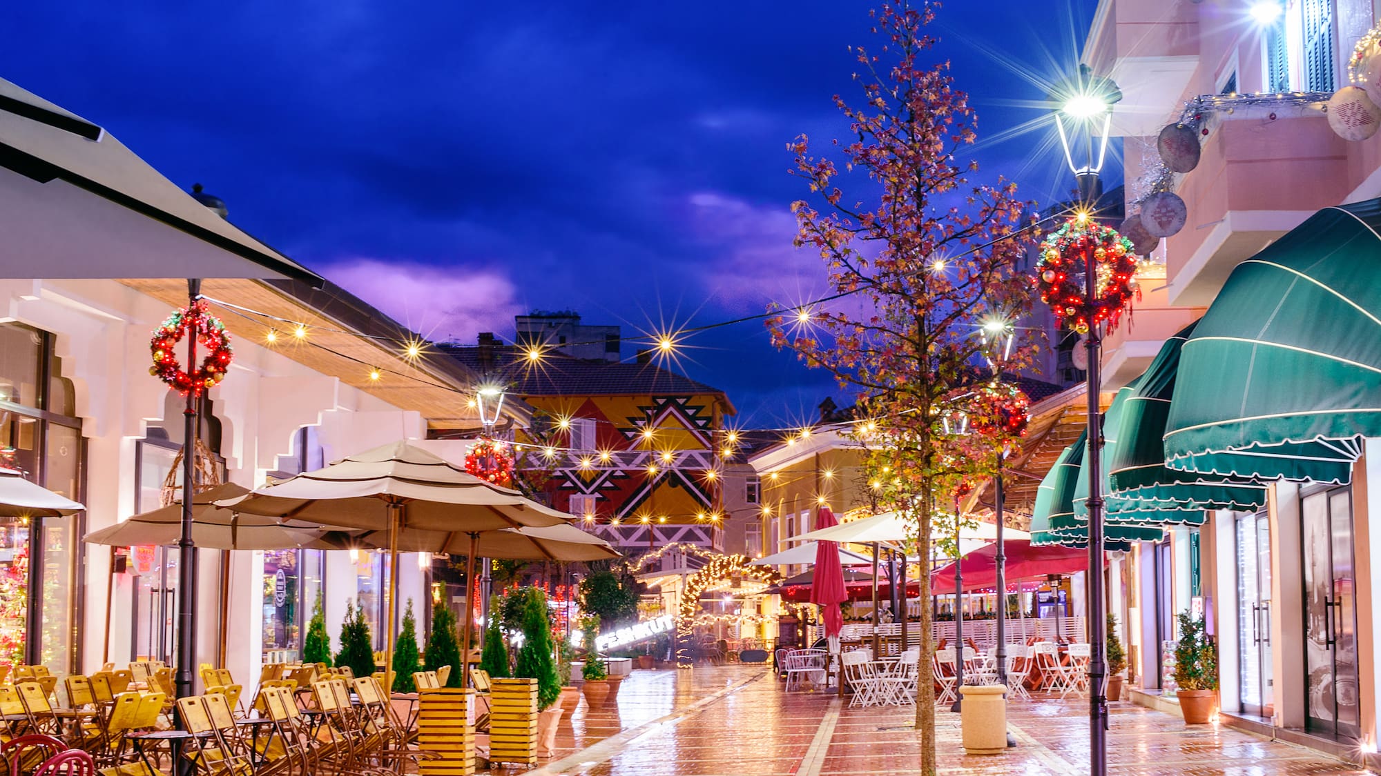 a street with tables and umbrellas and lights