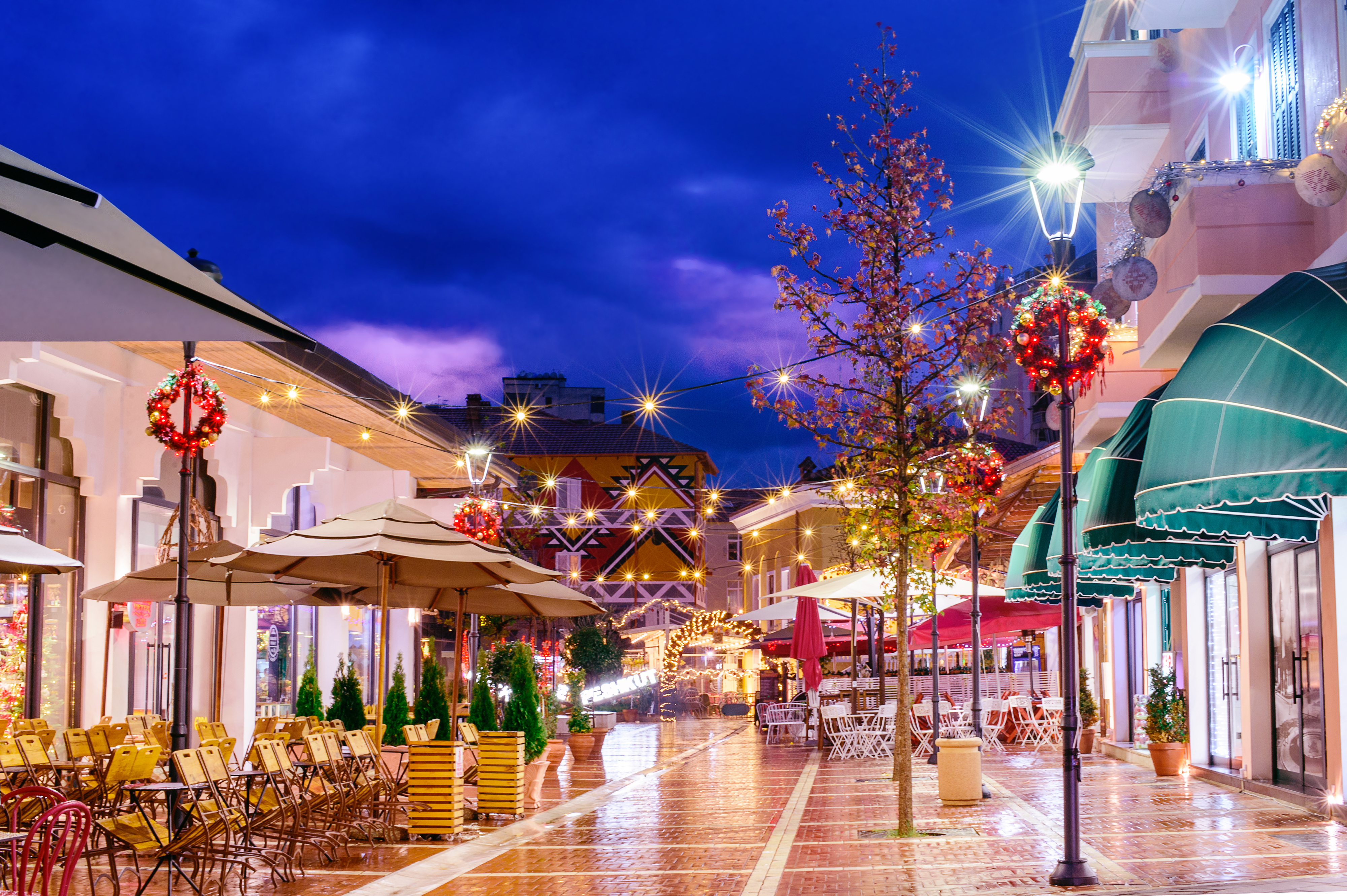 a street with tables and umbrellas and lights