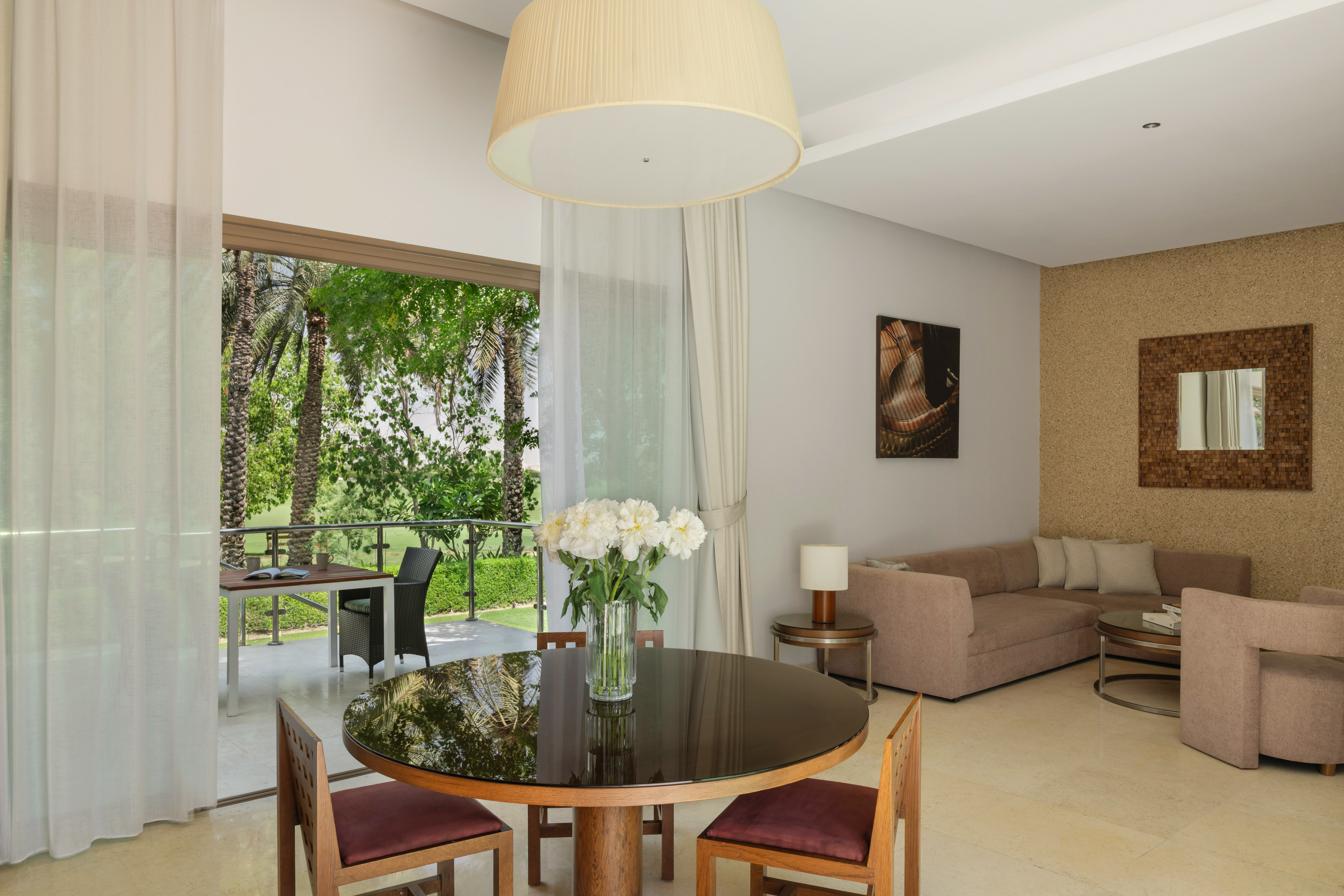 Modern living room and dining area with outdoor patio view of palm trees.