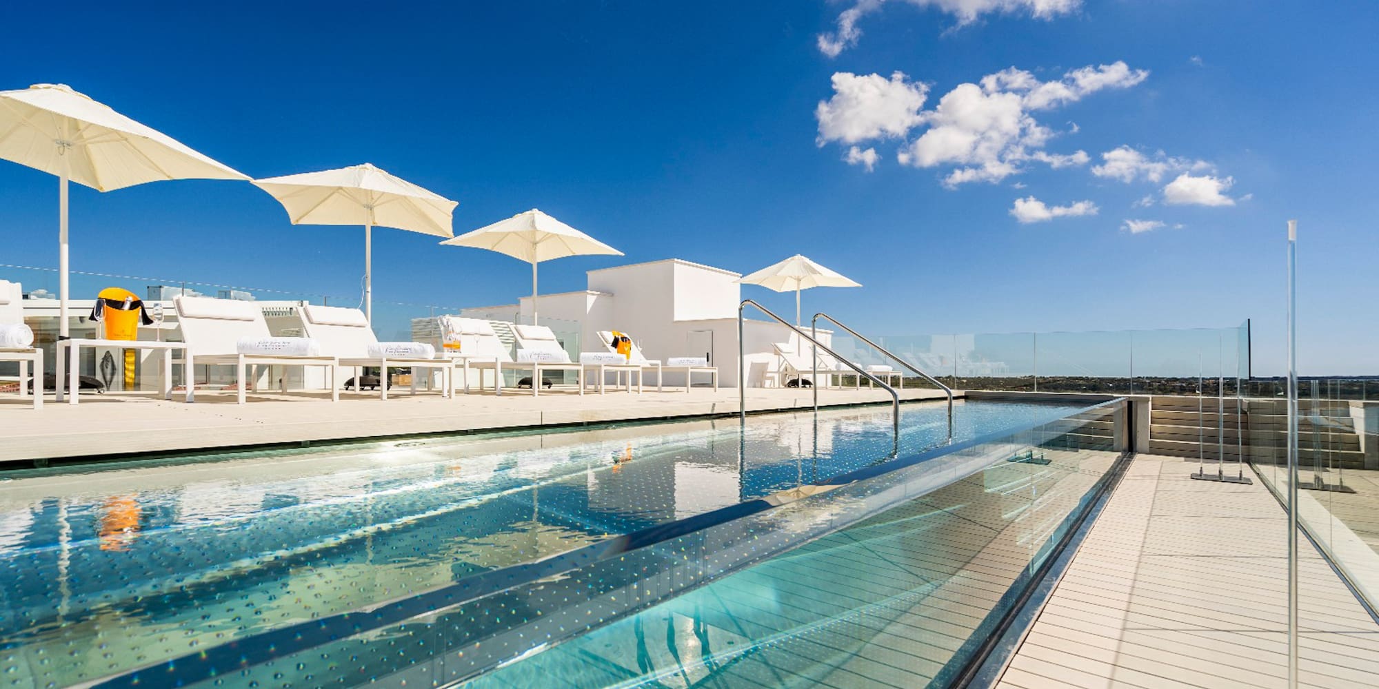 a pool with umbrellas and chairs on a rooftop