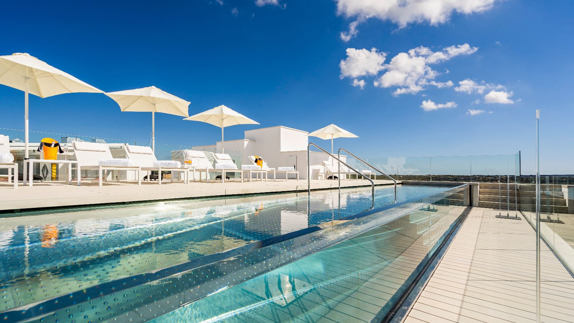 a pool with umbrellas and chairs on a rooftop