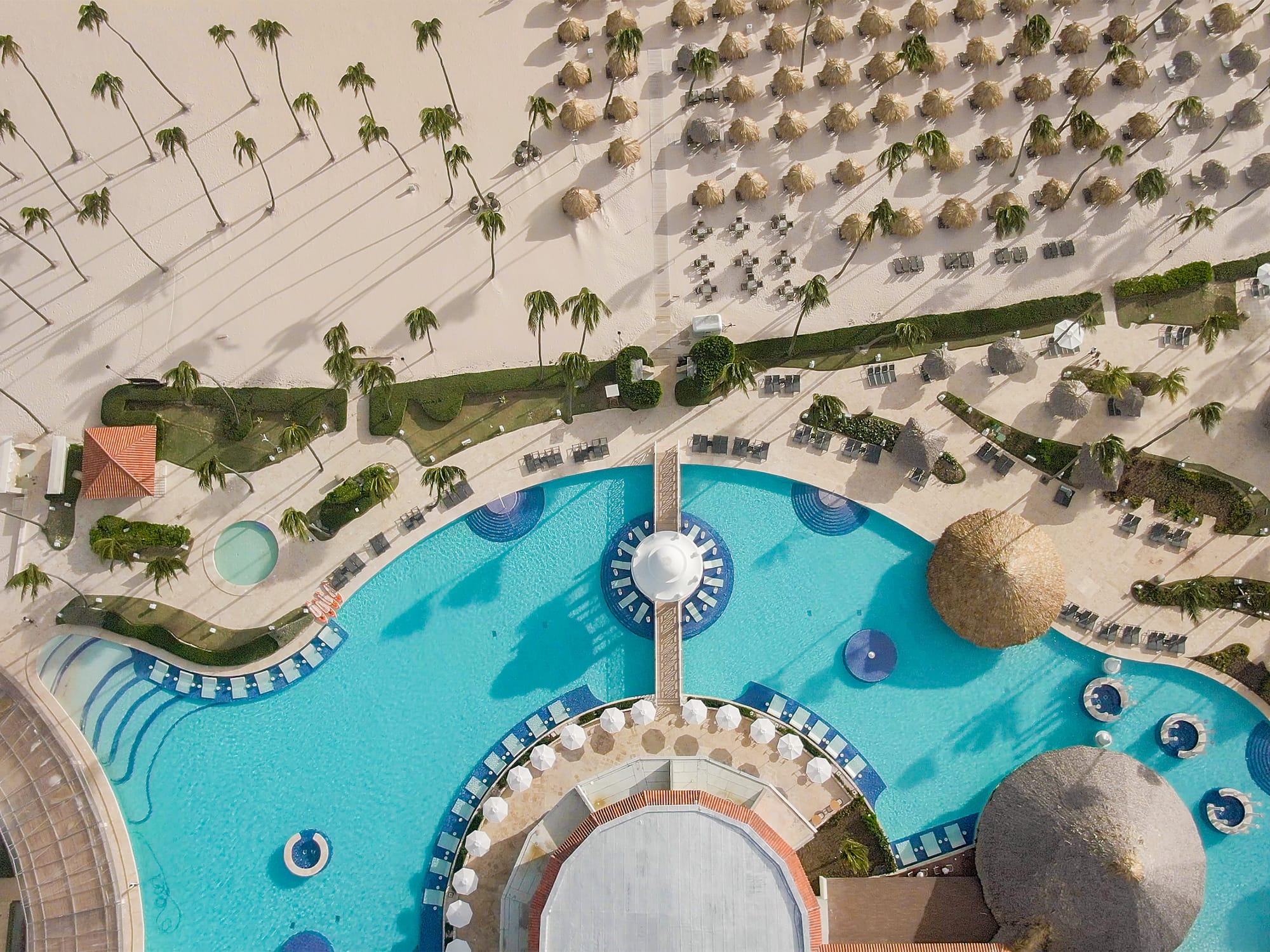an aerial view of a resort with a pool and palm trees