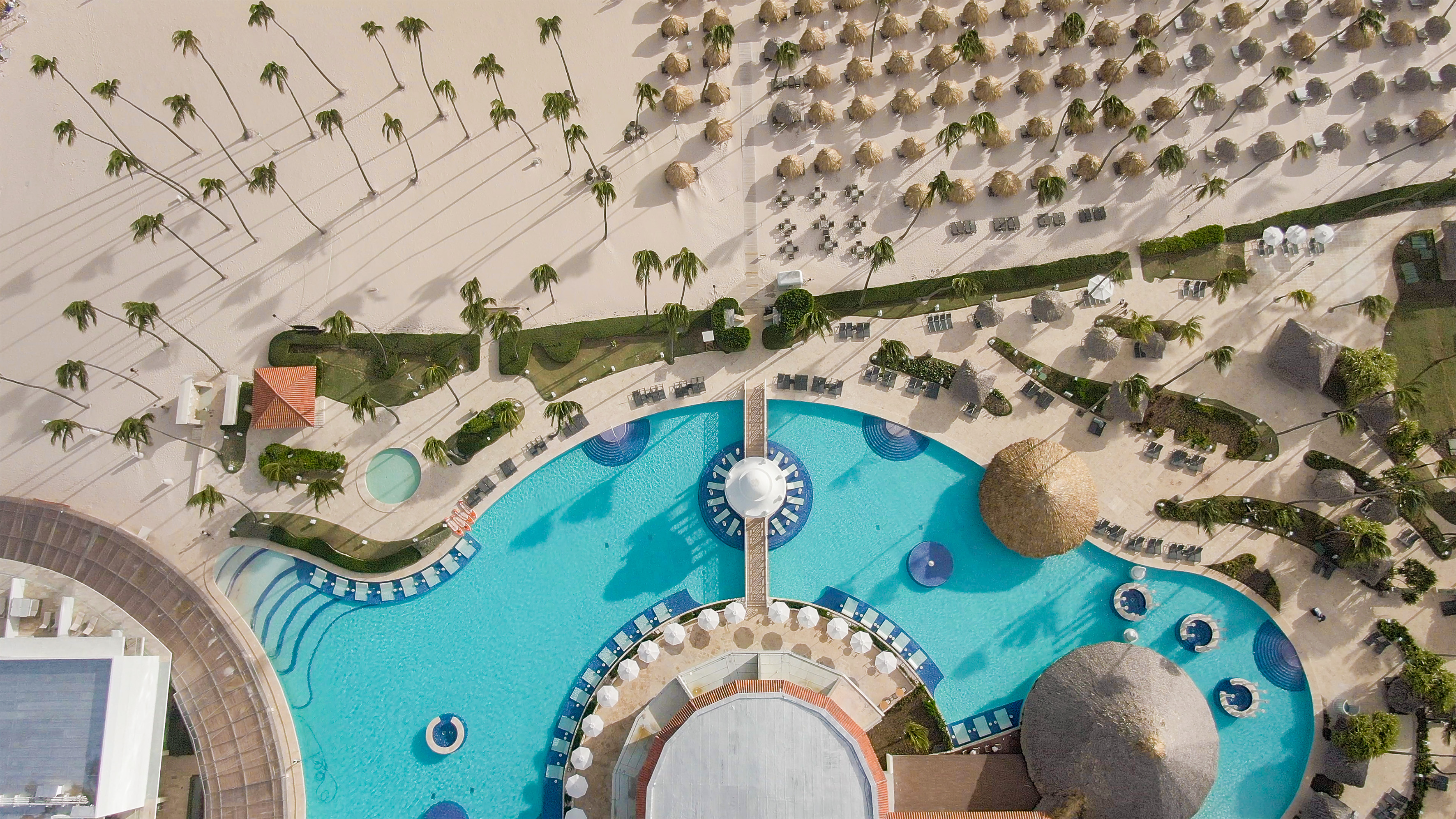 an aerial view of a resort with a pool and palm trees