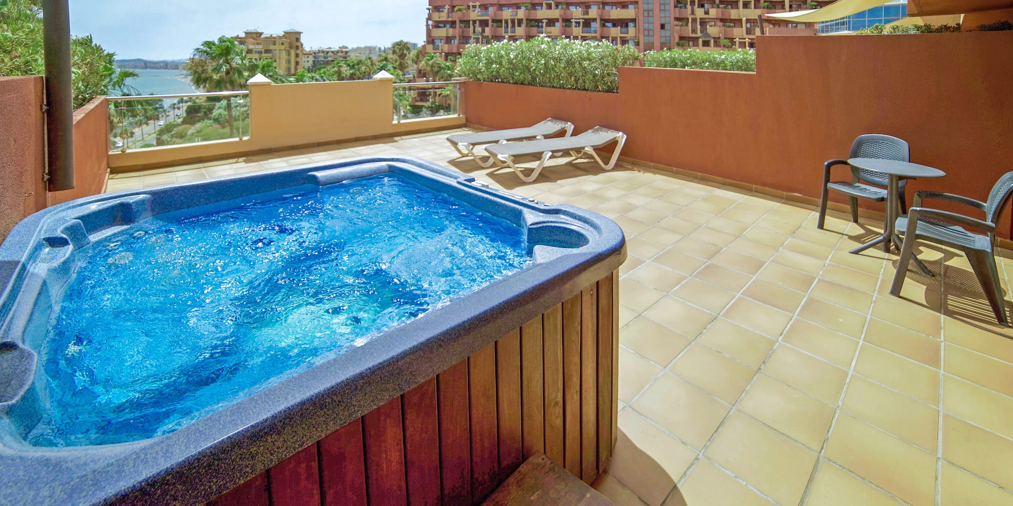 a hot tub on a patio with a deck chair and a building
