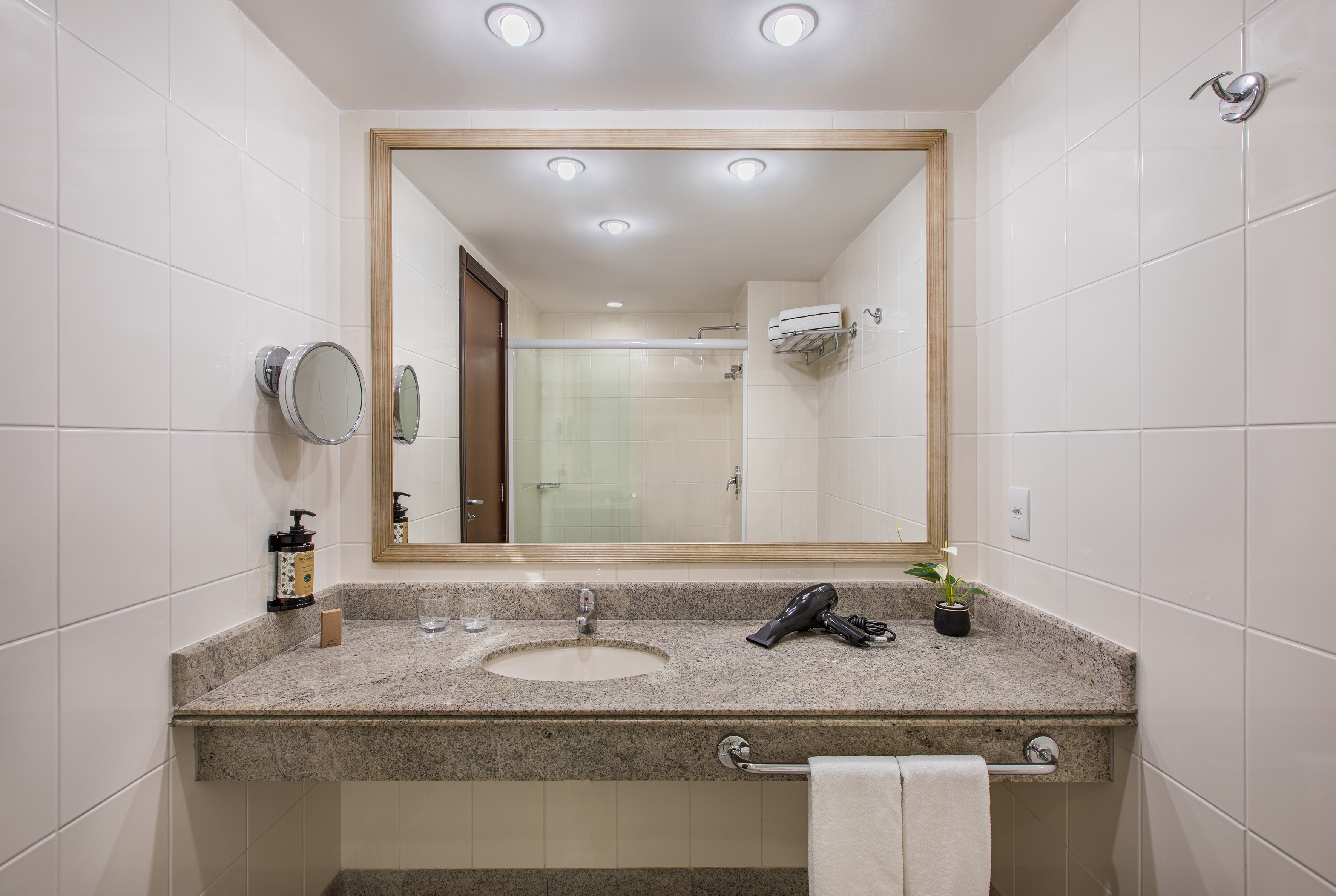 Clean hotel bathroom vanity with granite counter, sink, and large mirror.