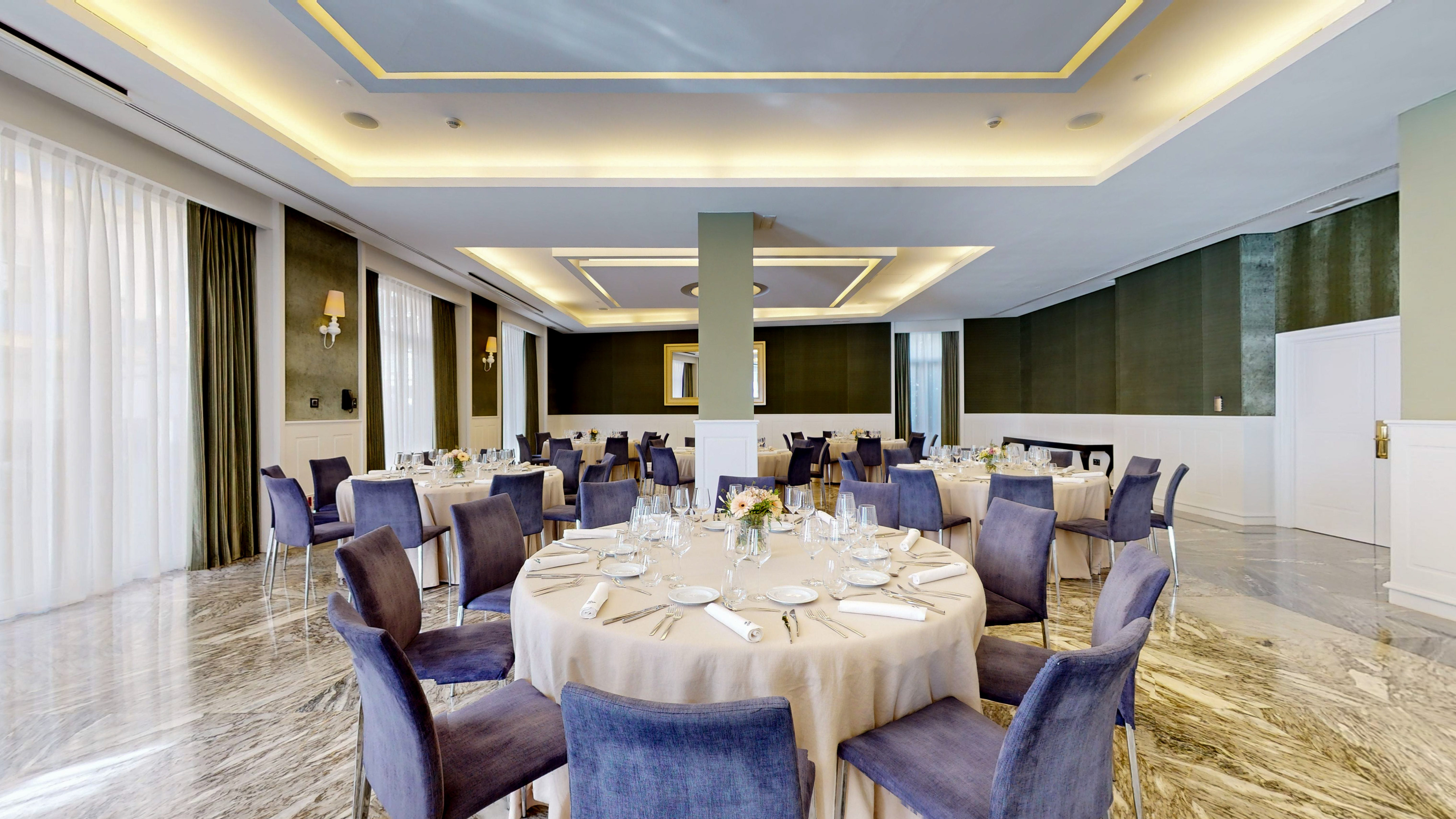Elegant hotel event room with round tables, purple chairs, and marble floor.