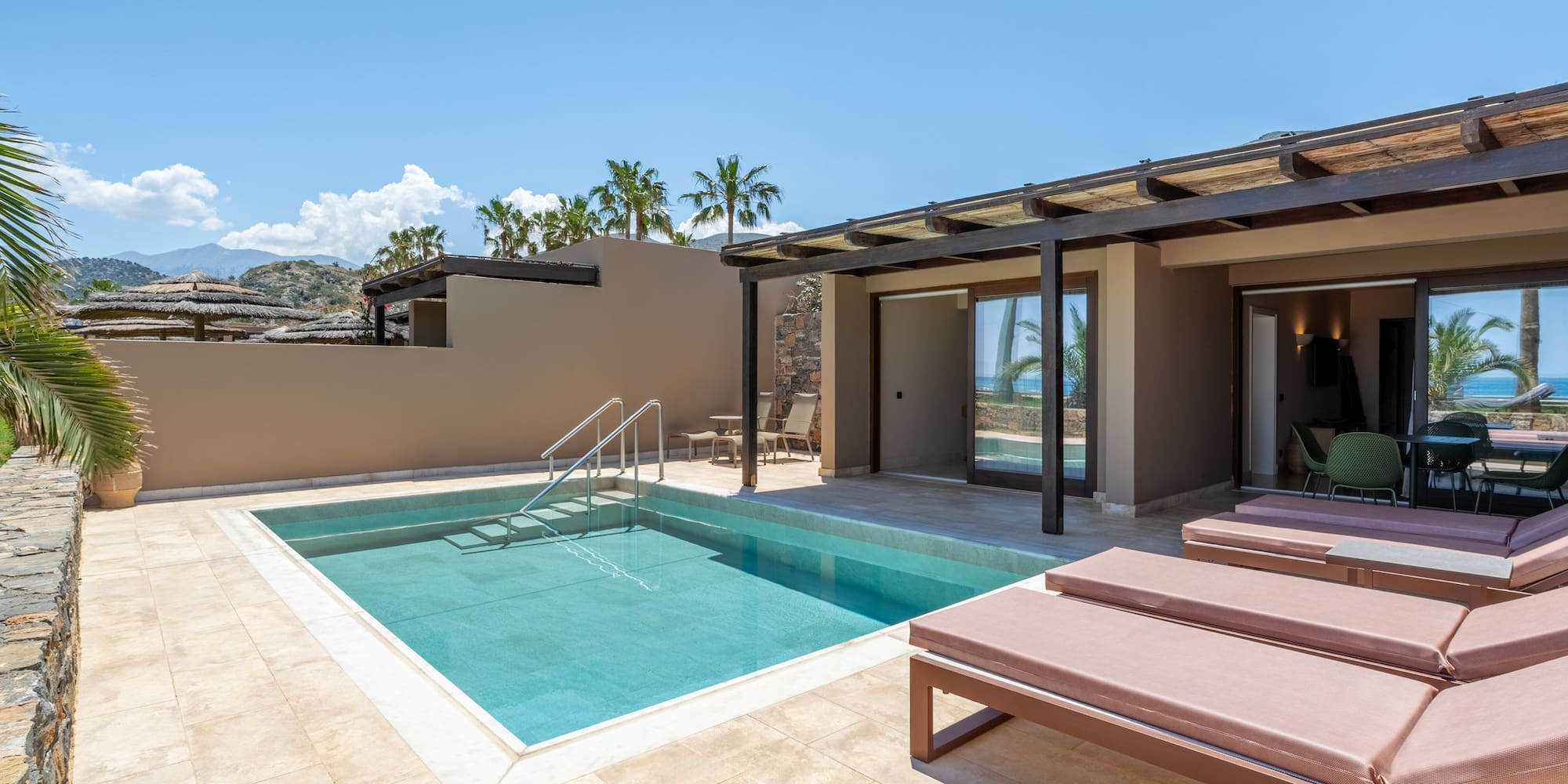 Modern hotel suite with private pool, sunbeds, and ocean view patio.