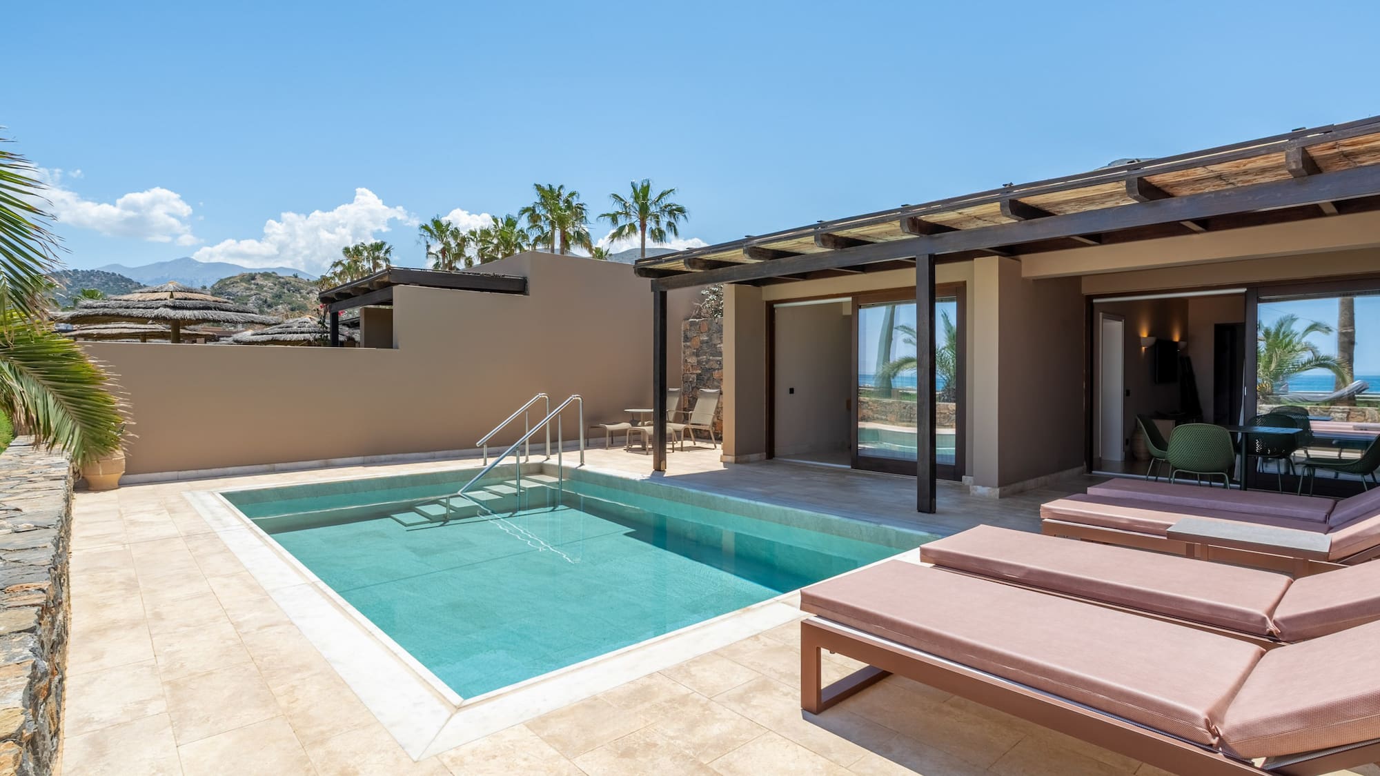 Modern hotel suite with private pool, sunbeds, and ocean view patio.