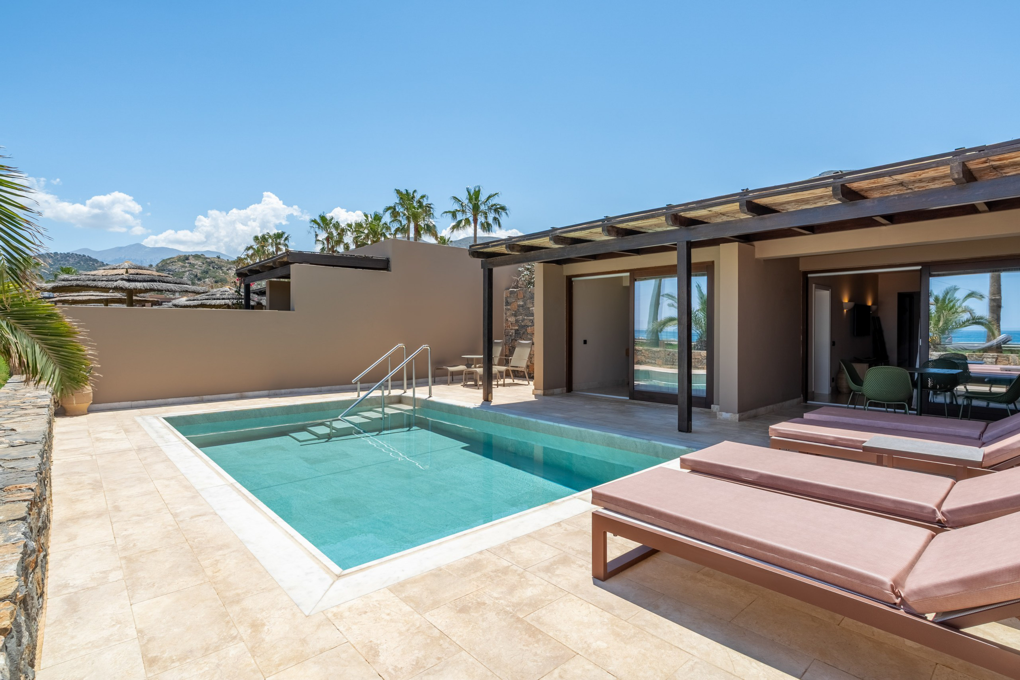 Modern hotel suite with private pool, sunbeds, and ocean view patio.