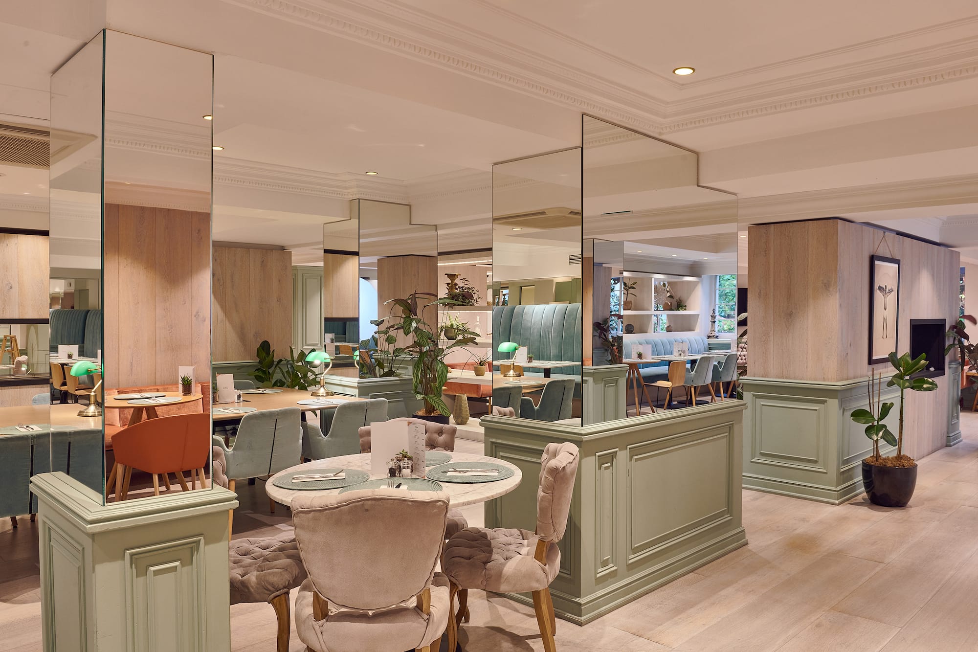 Modern restaurant dining room with elegant velvet chairs and sage green accents.