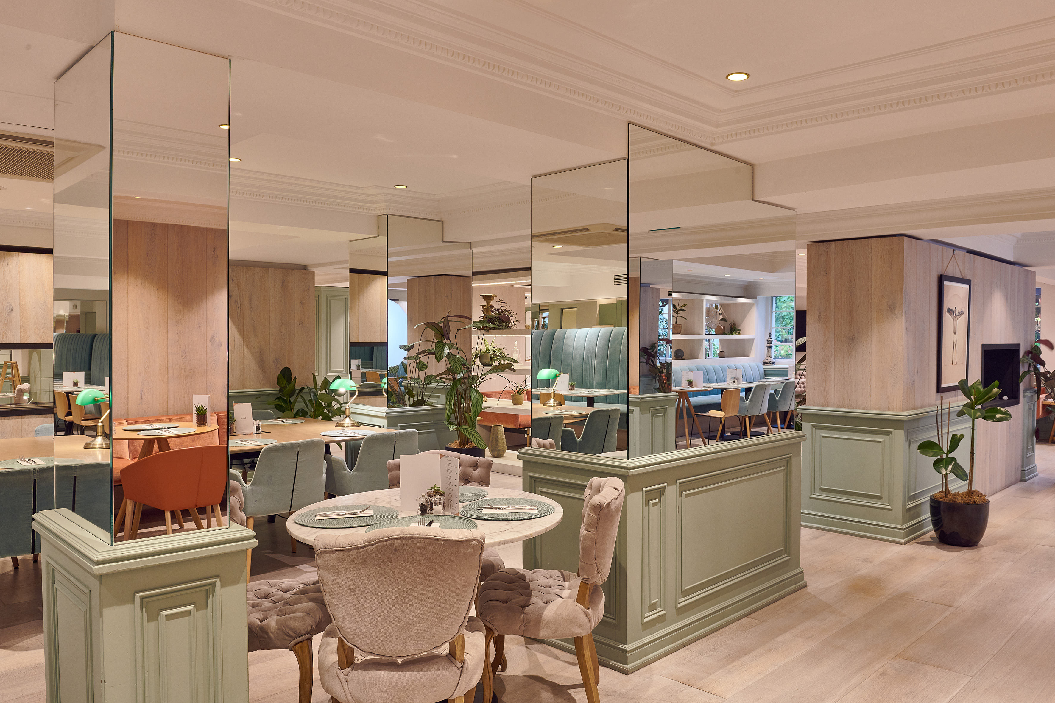Modern restaurant dining room with elegant velvet chairs and sage green accents.