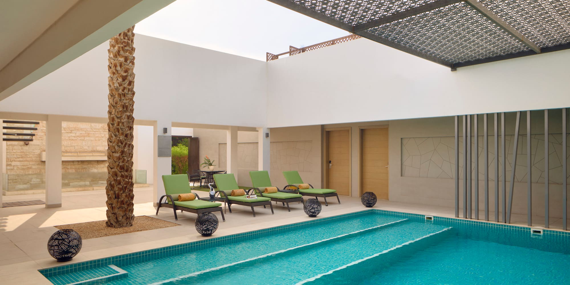 a pool with lounge chairs and a tree