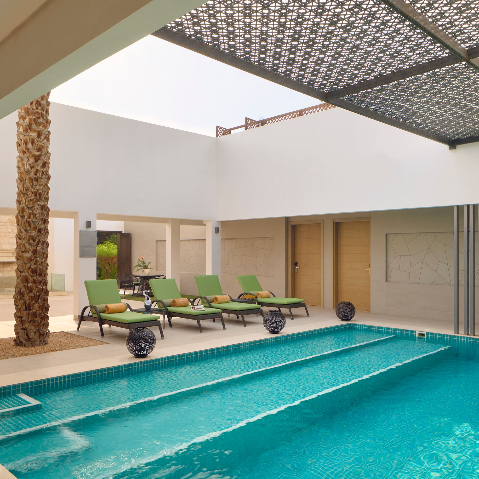 a pool with lounge chairs and a tree