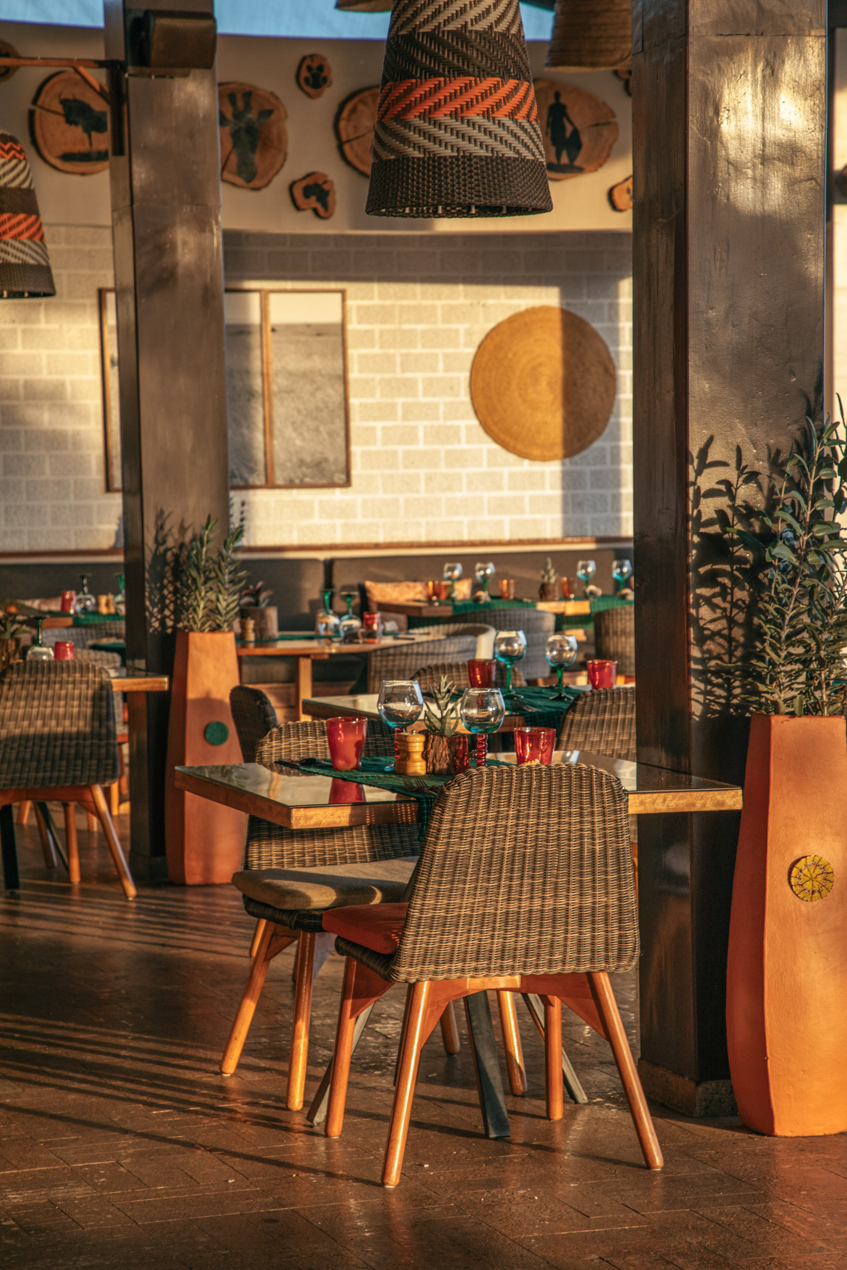 Warm restaurant dining area with wicker chairs and African-themed decor.