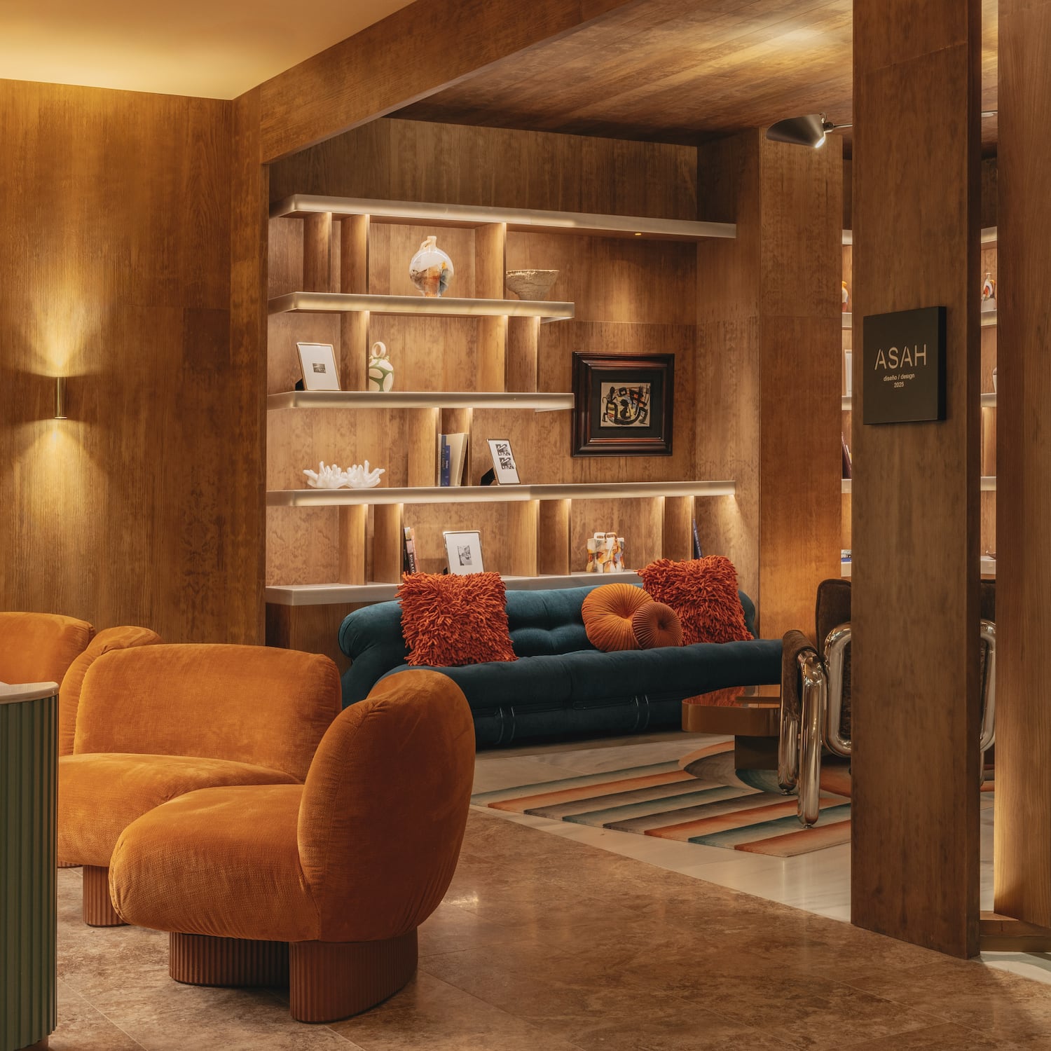 Modern lounge interior with warm wood walls, orange chairs, and ambient lighting.