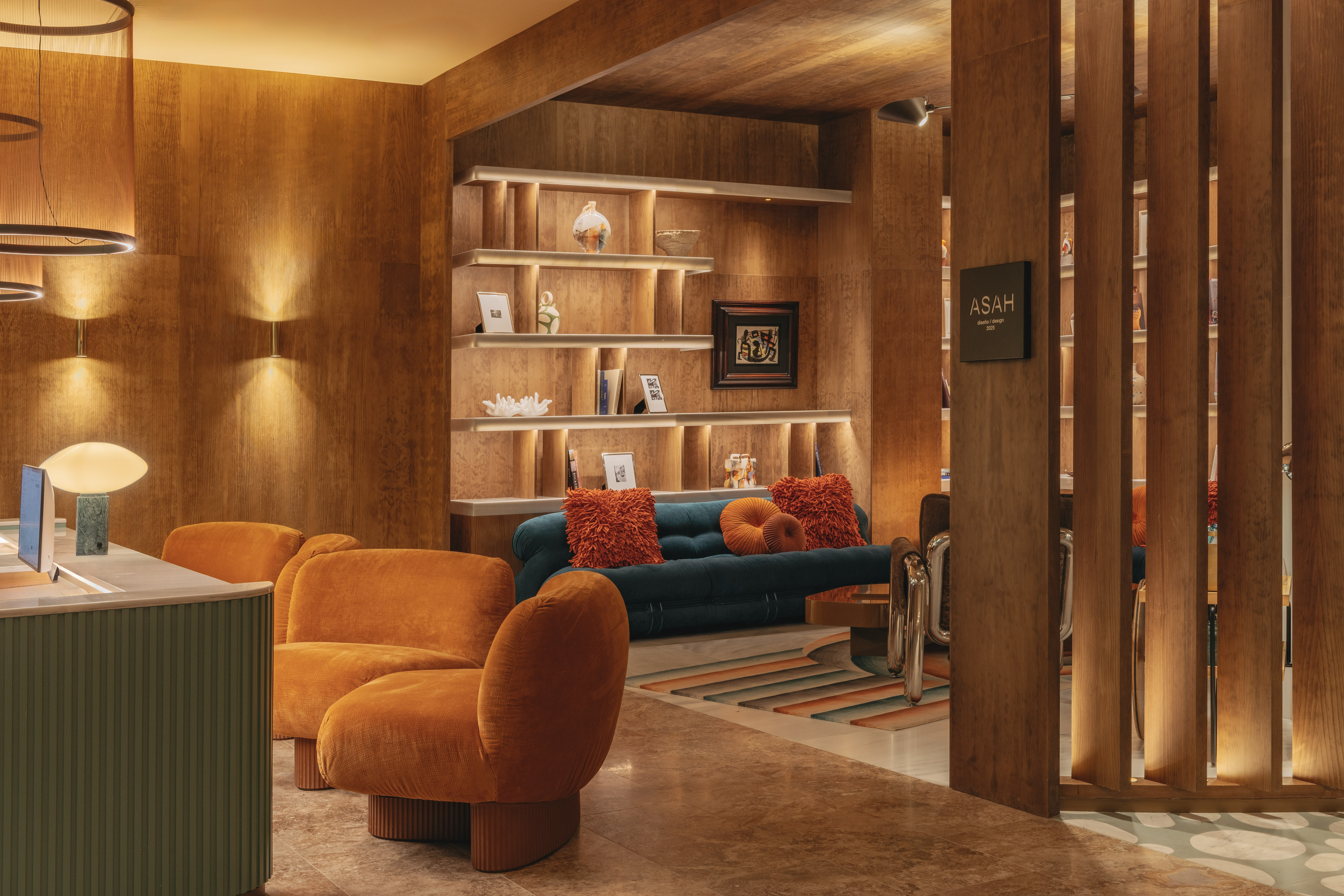 Modern lounge interior with warm wood walls, orange chairs, and ambient lighting.