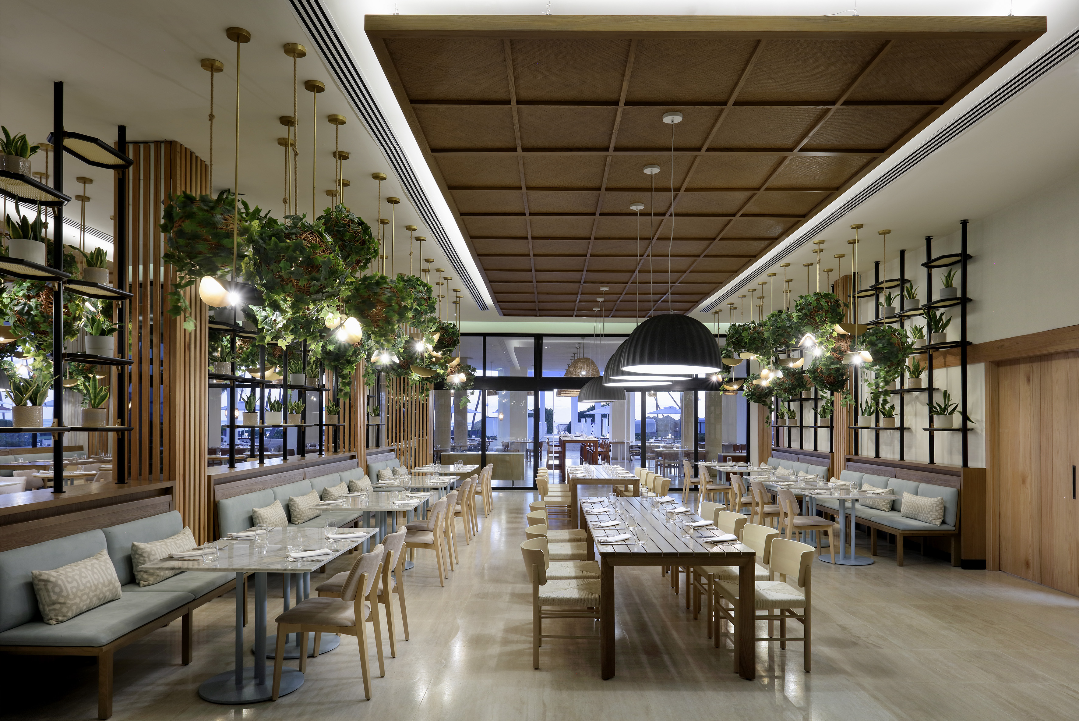 Botanical restaurant with wooden ceiling, hanging plants, and elegant tables.