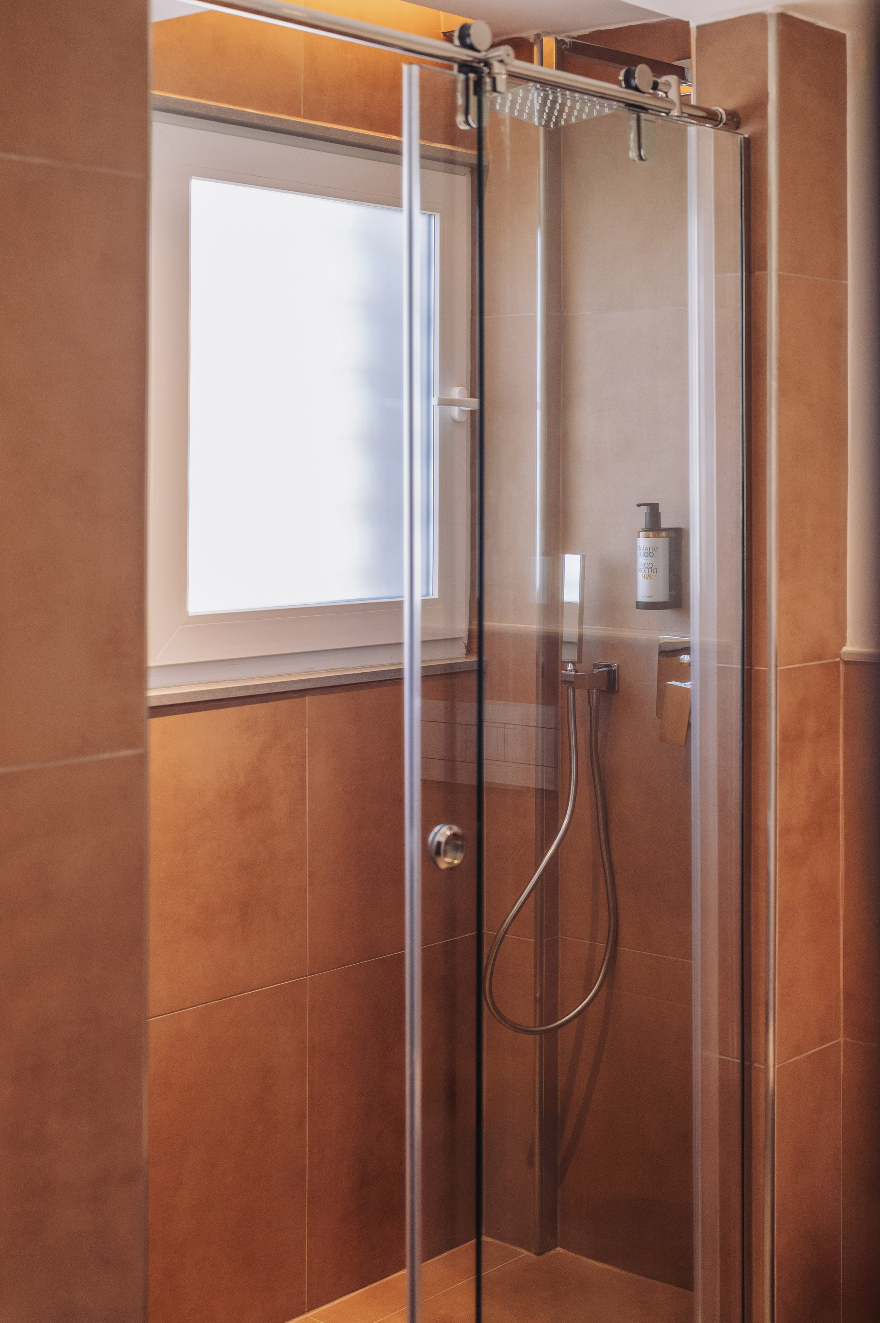 Contemporary shower, glass enclosure, rain shower, and brown tiled walls.