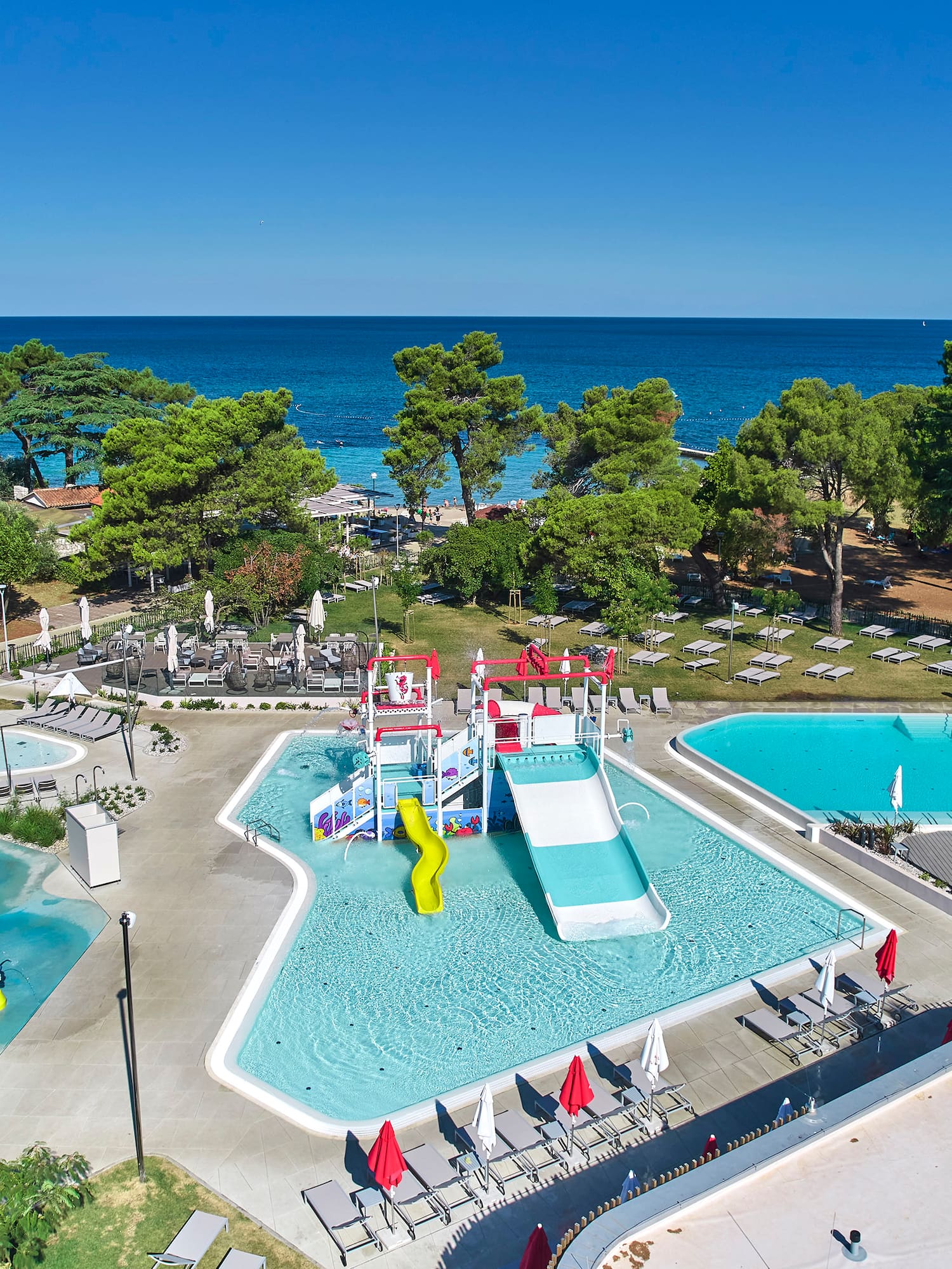 a swimming pool with trees and chairs and a water park