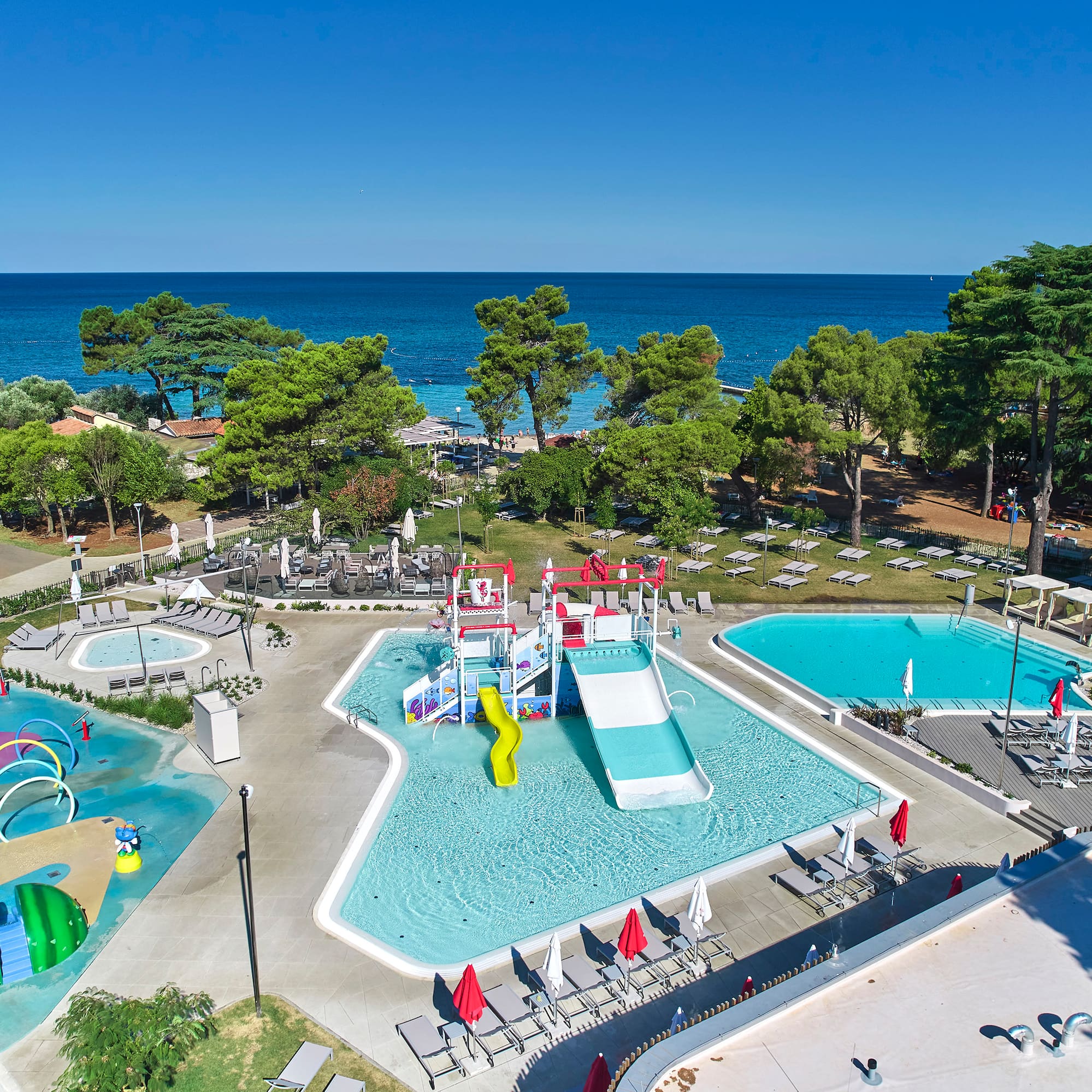 a swimming pool with trees and chairs and a water park