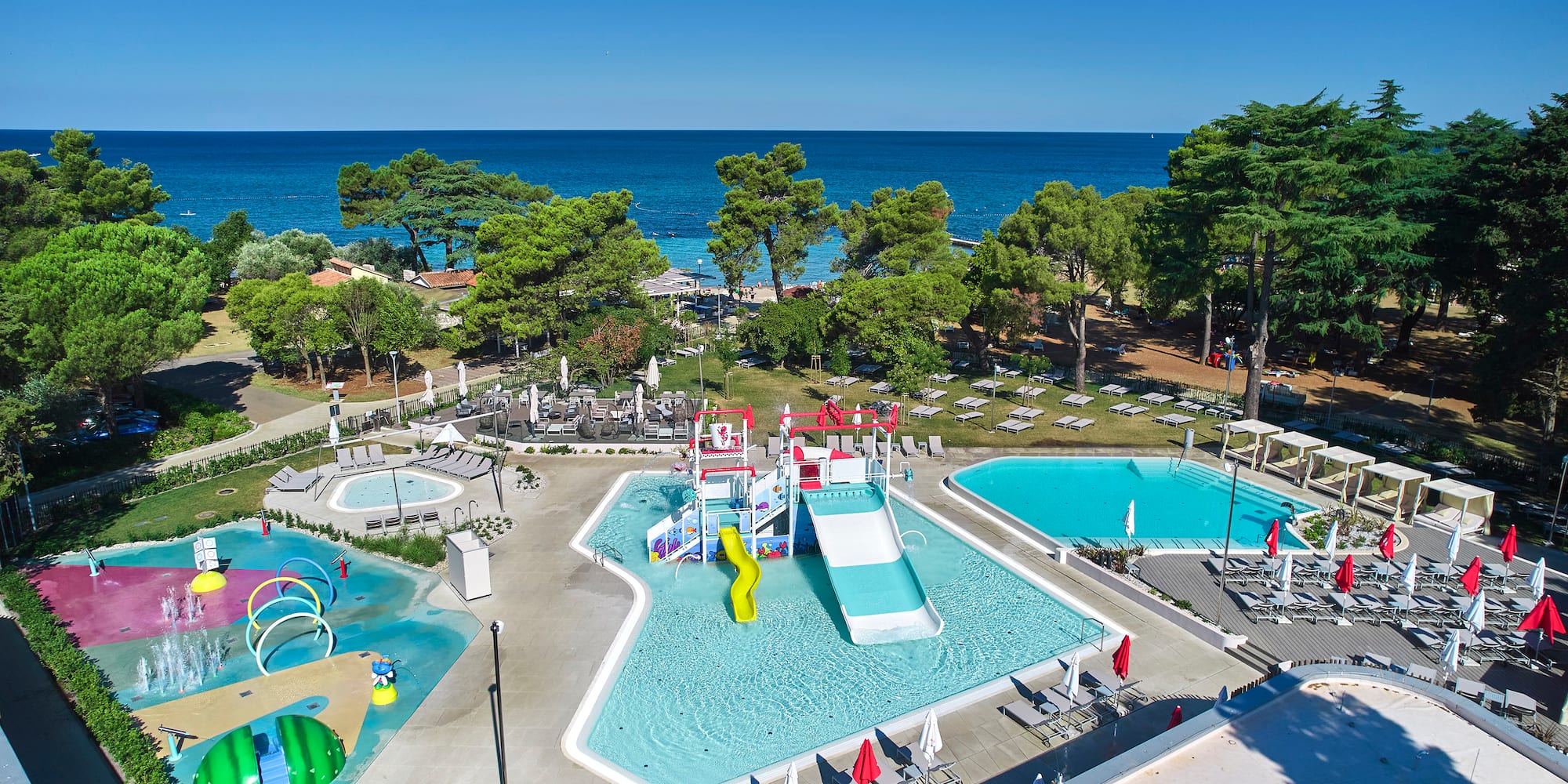 a swimming pool with trees and chairs and a water park