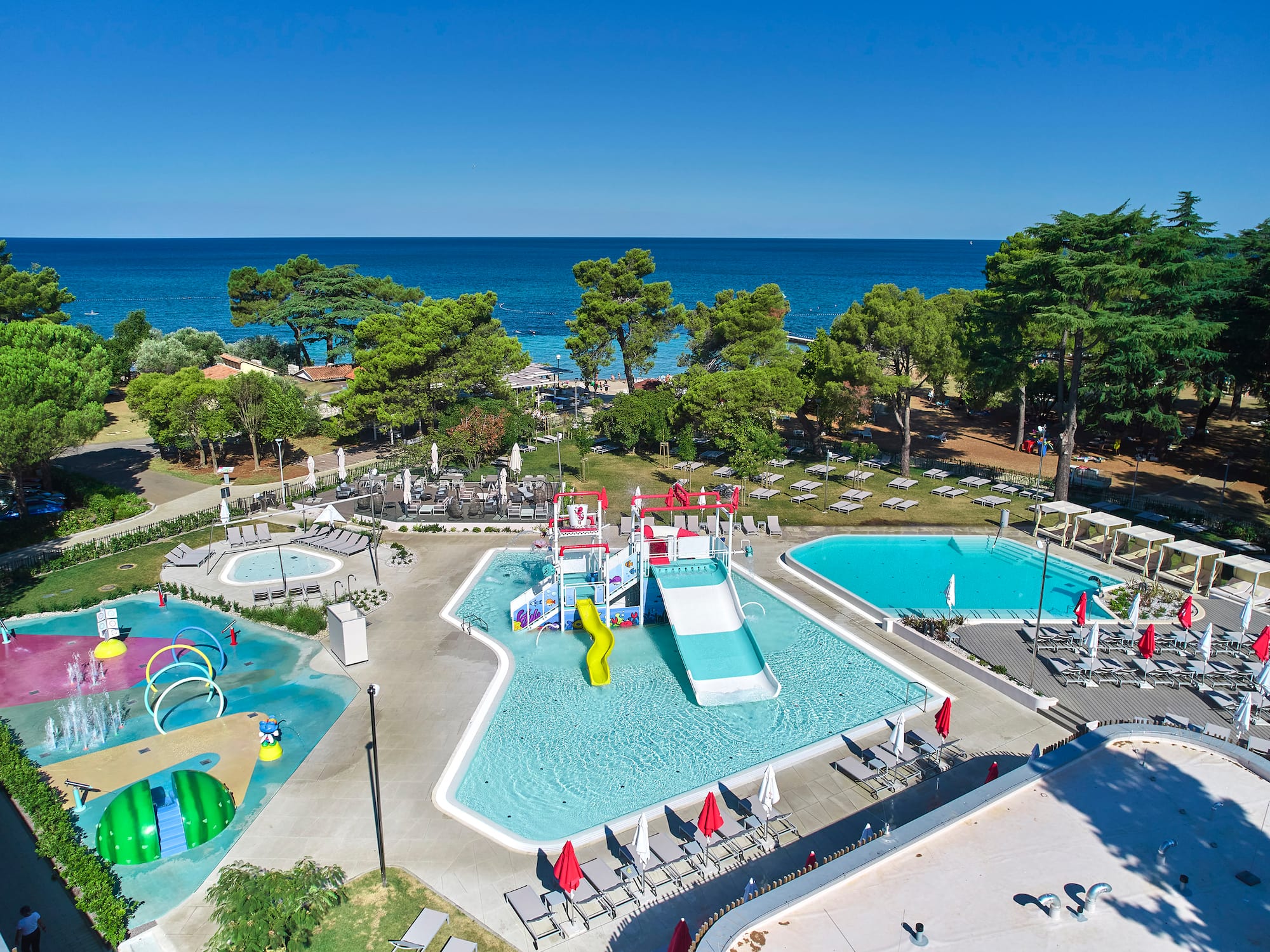 a swimming pool with trees and chairs and a water park