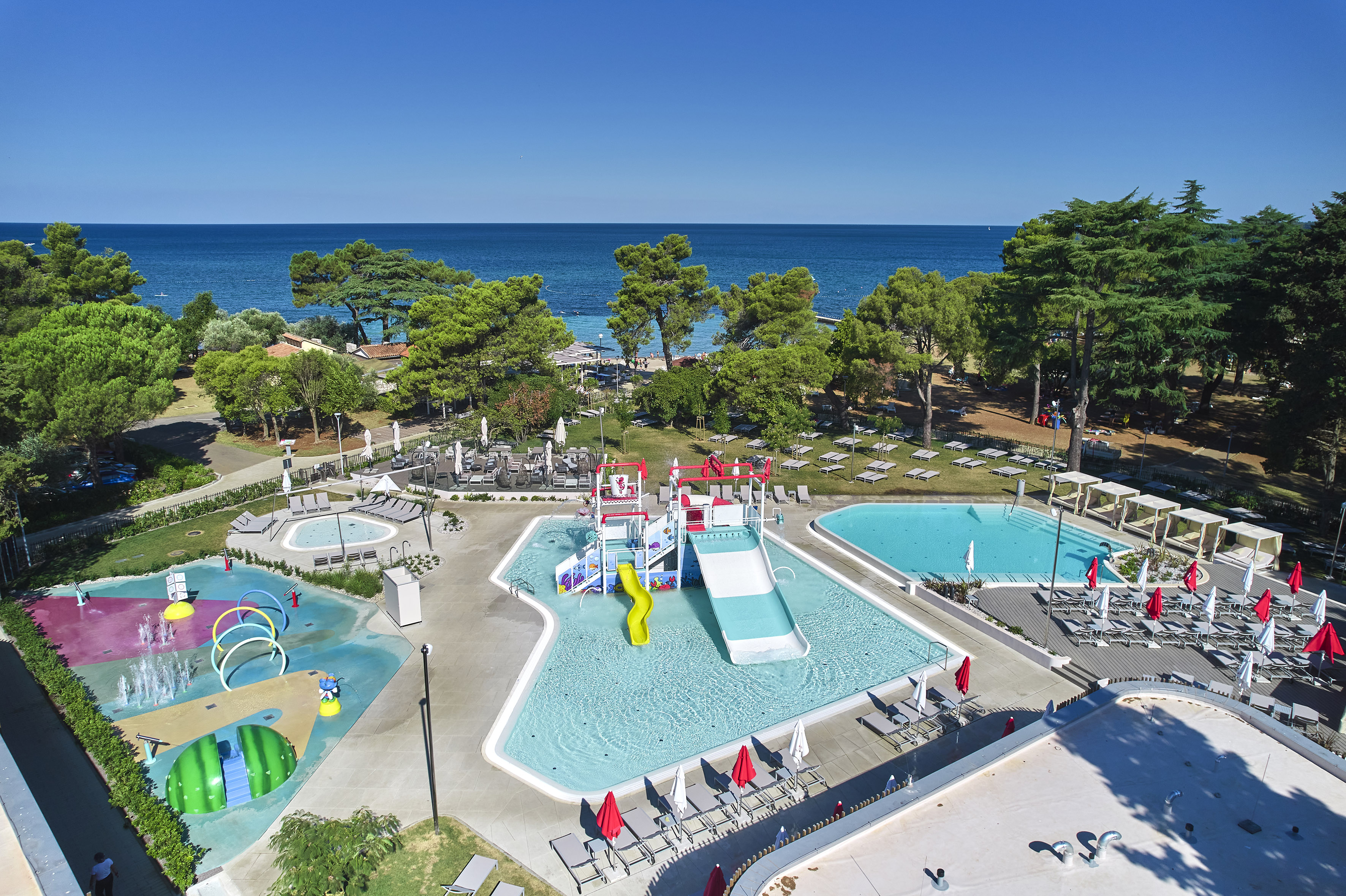 a swimming pool with trees and chairs and a water park