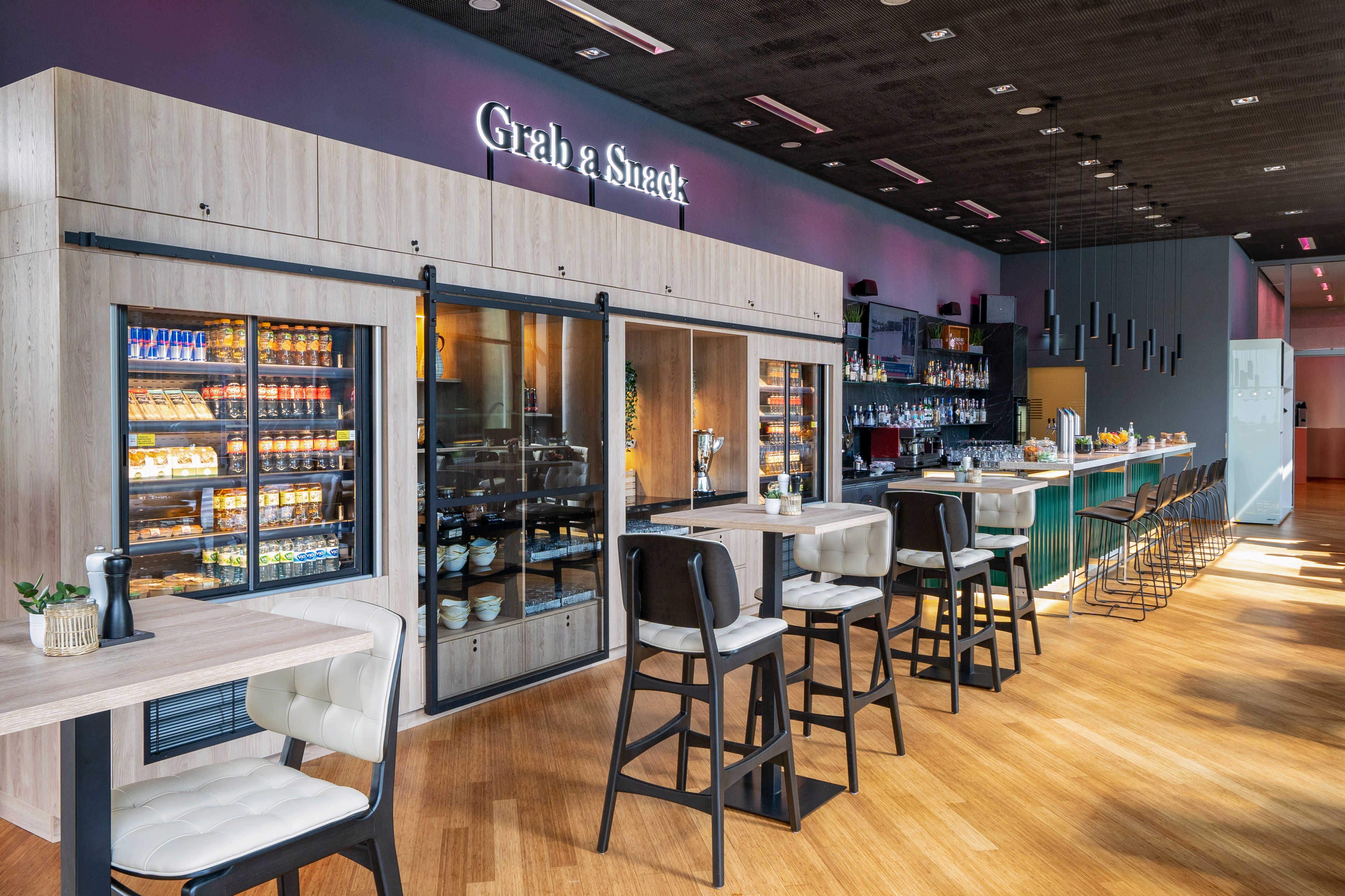 Modern "Grab a Snack" bar with refrigerated food displays, drinks, and seating.
