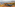 Grey 4x4 on a rocky coastal track, Mediterranean sea, distant village.