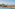 Tropical infinity pool, palm trees, sandy beach, and blue ocean.