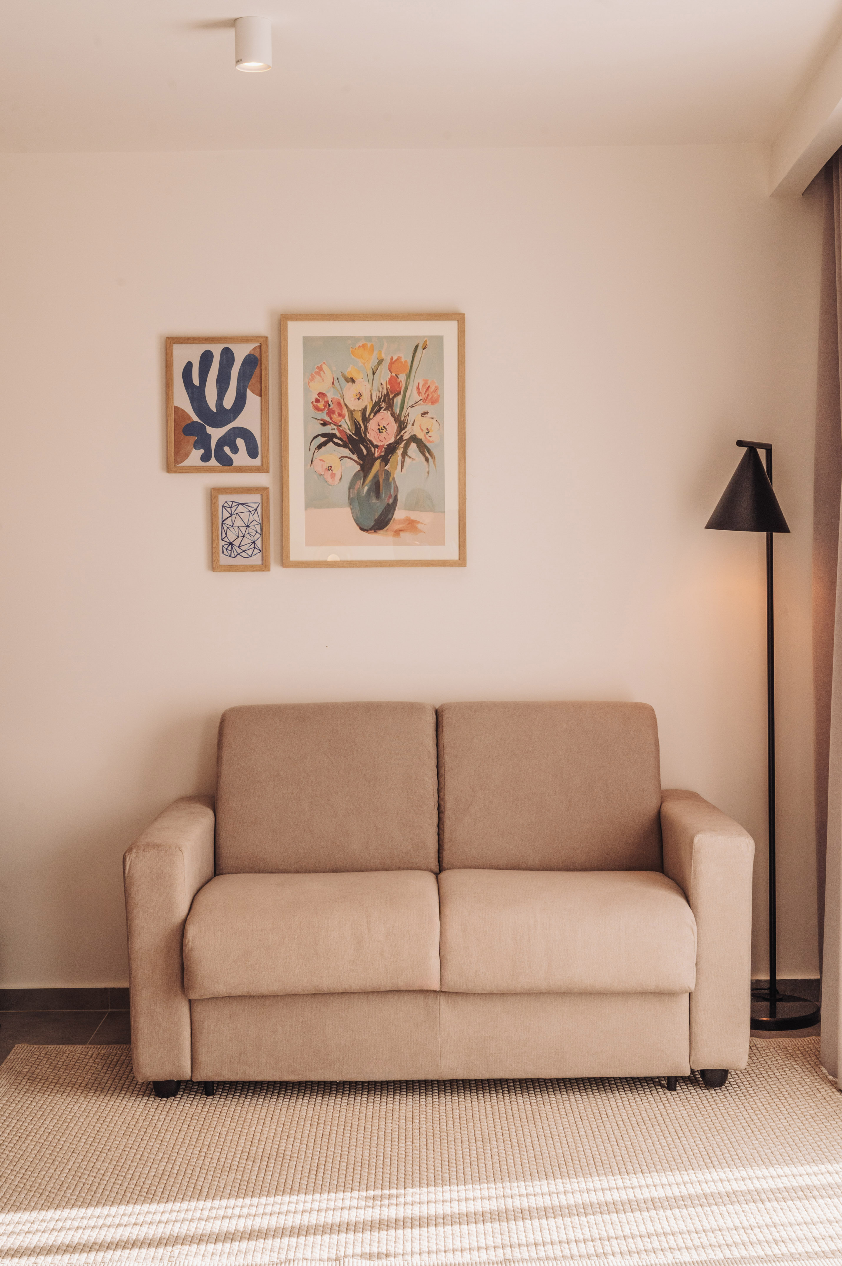 Neutral modern living room with beige sofa, framed art, and black floor lamp.