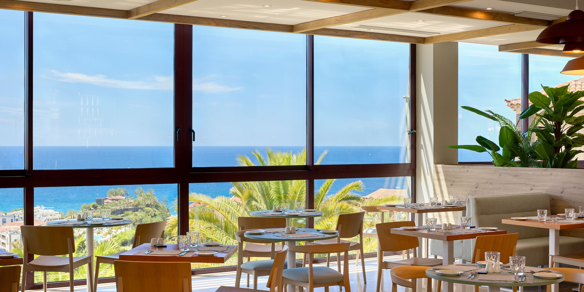 a room with tables and chairs and a view of the ocean