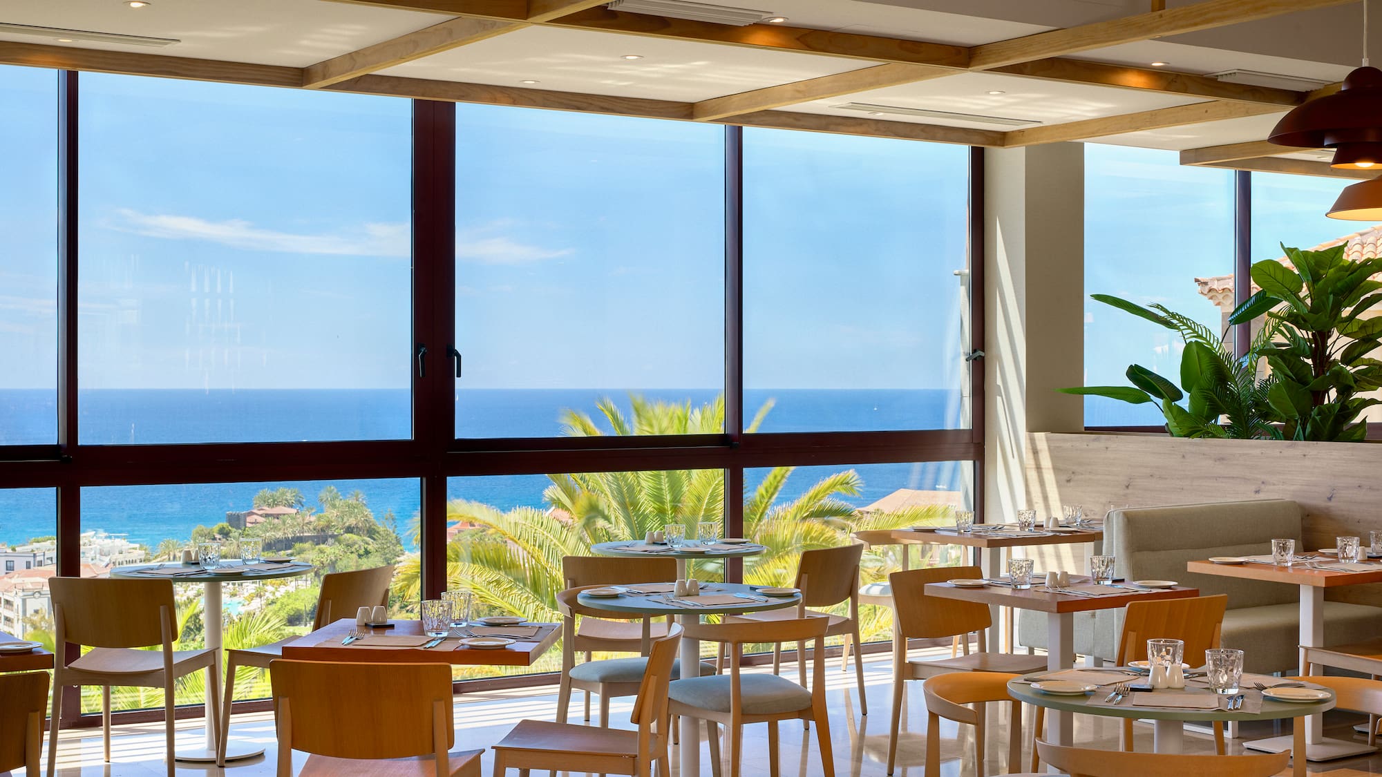 a room with tables and chairs and a view of the ocean