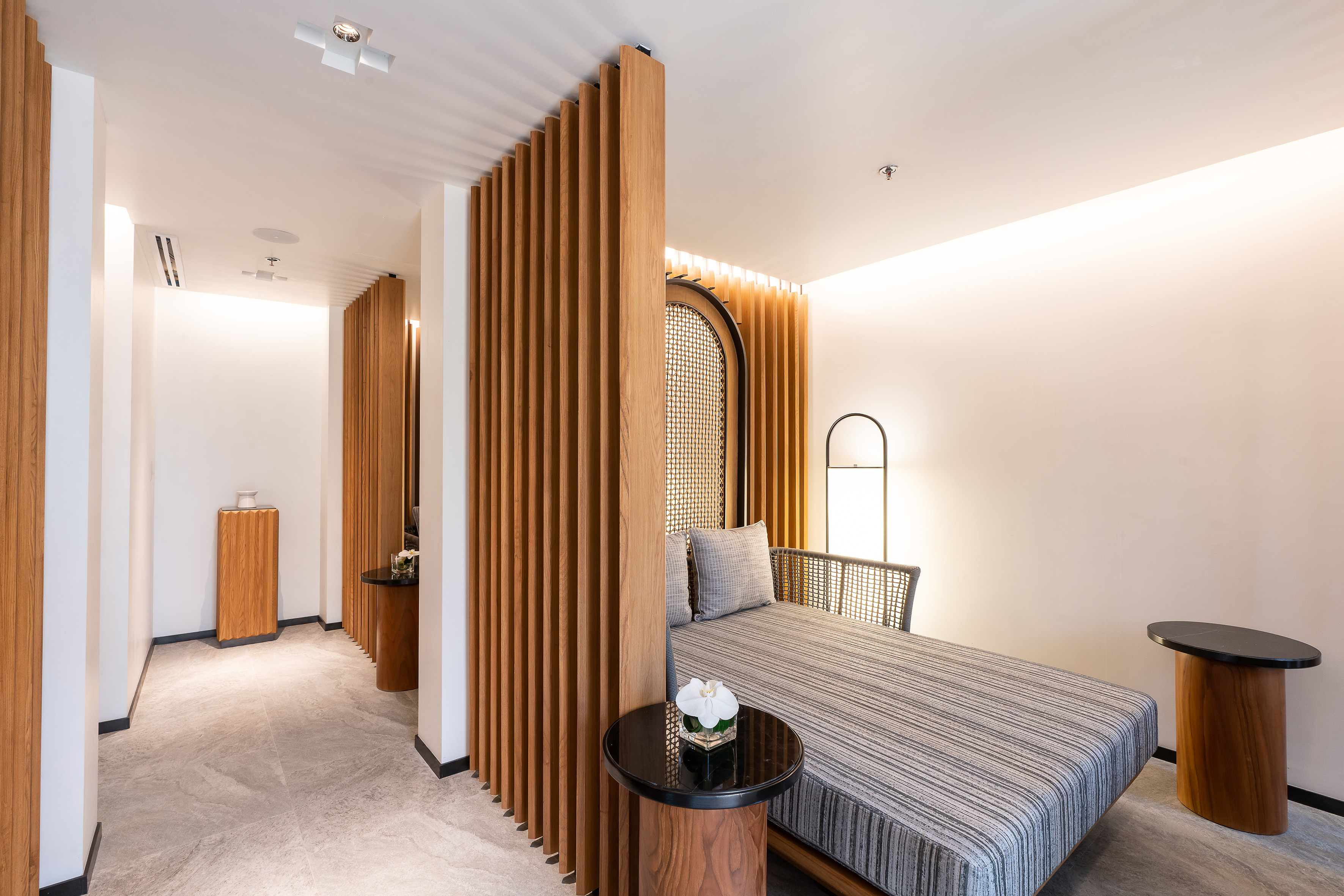 Modern lounge with wooden slatted screen, daybed, and ambient lighting.