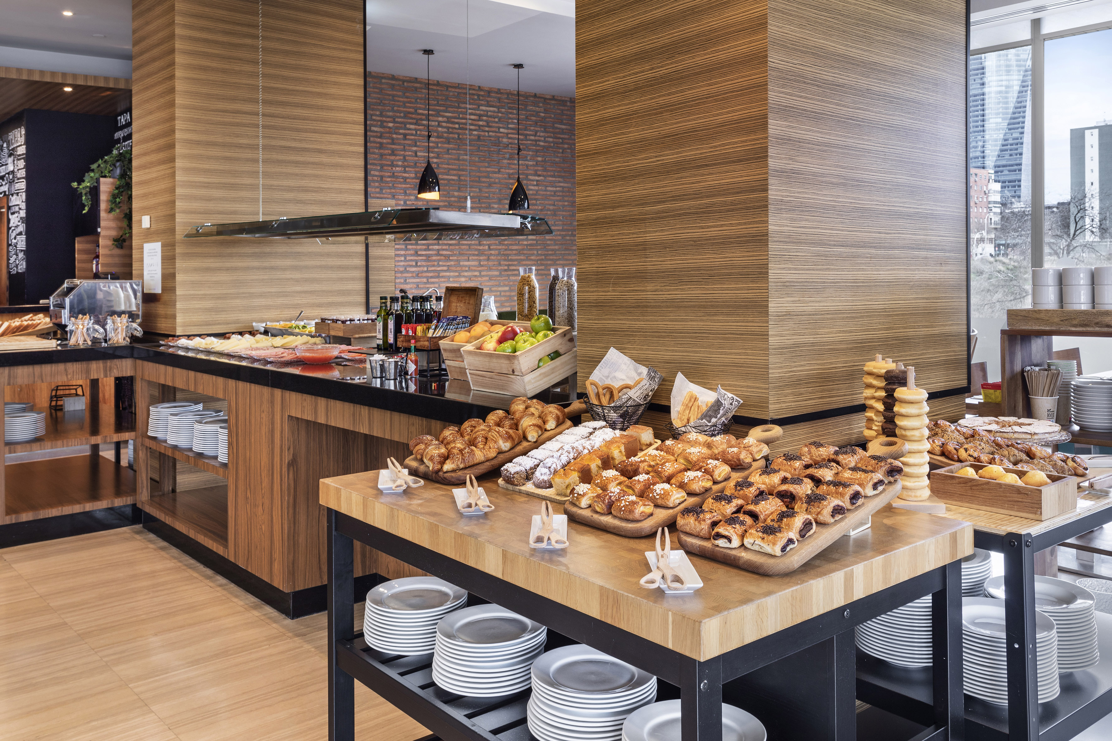 Spacious hotel breakfast buffet with pastries, fresh fruit, cereals, and cold cuts.
