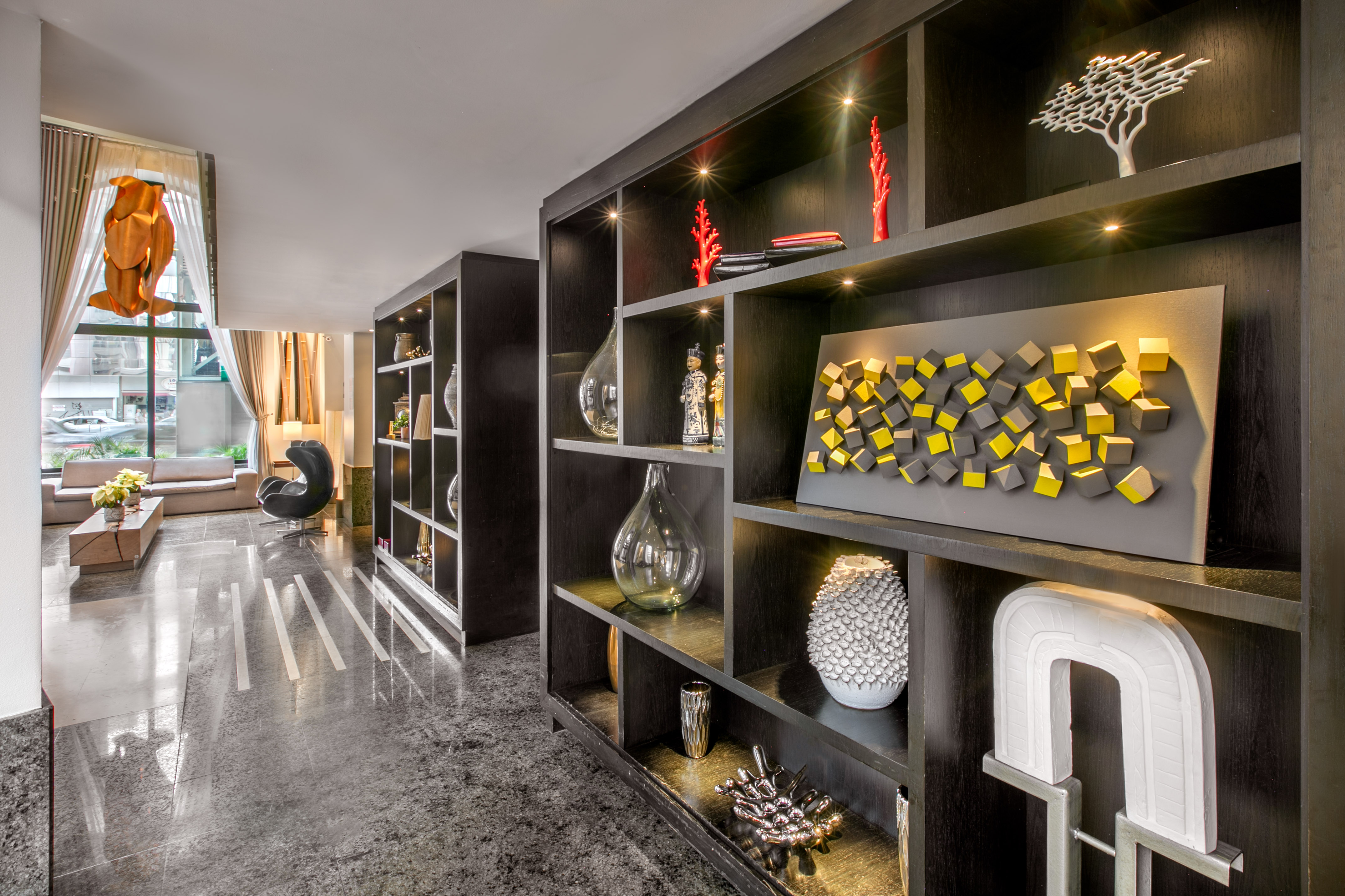 Modern lobby with dark decorative shelving, diverse decor, and polished floor.