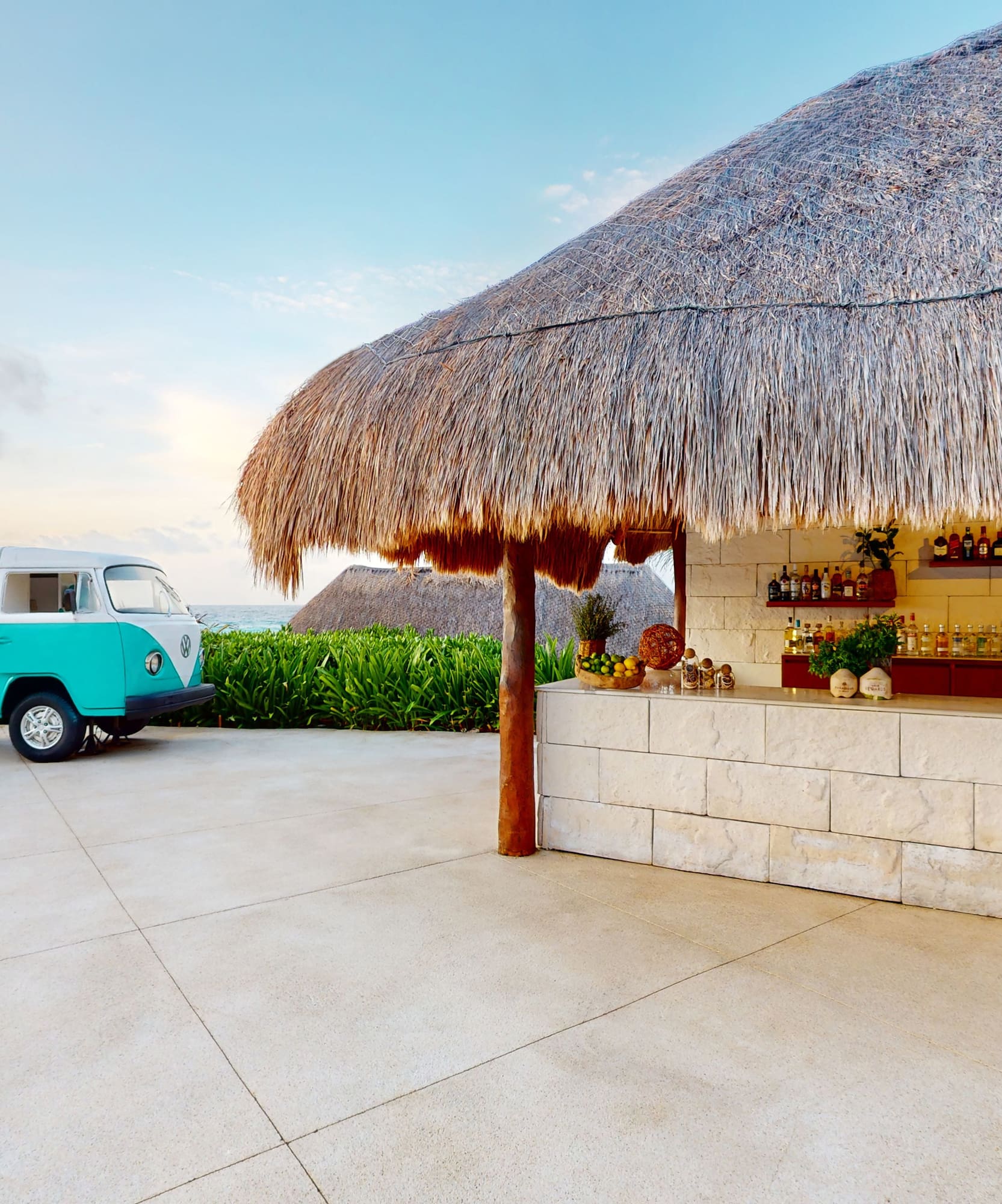 a bar with a blue van parked in front of a thatched roof
