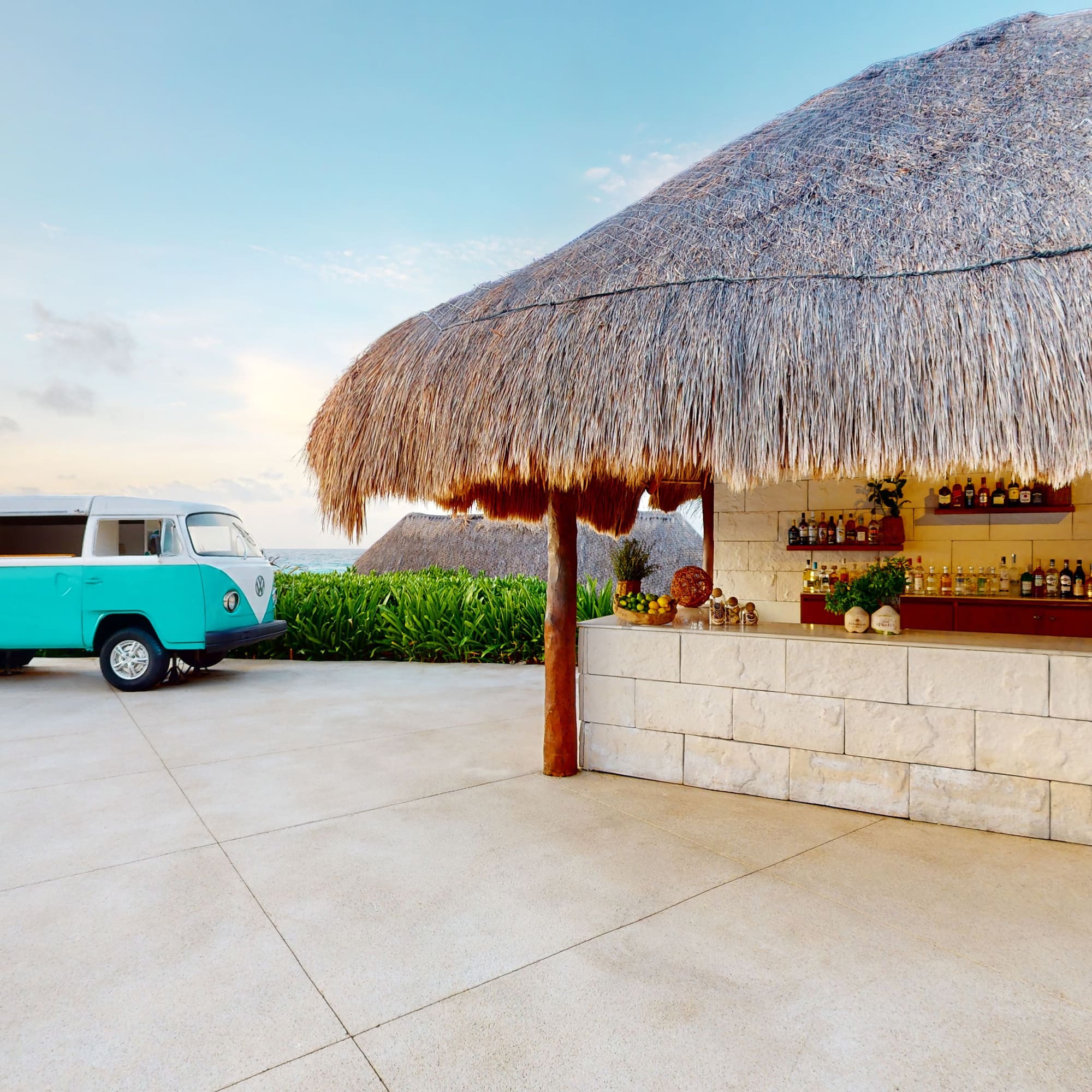 a bar with a blue van parked in front of a thatched roof