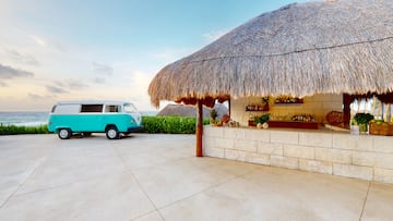 a bar with a blue van parked in front of a thatched roof