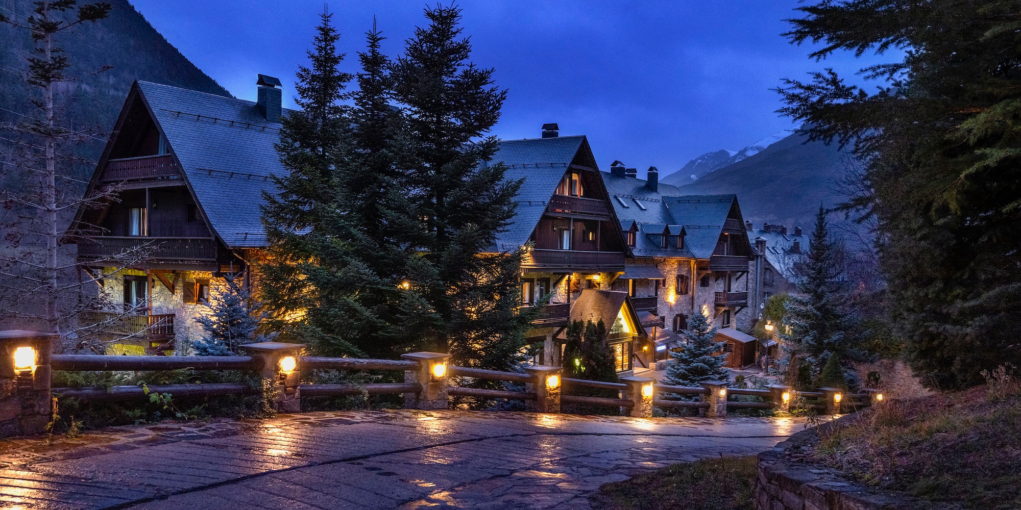 a stone walkway with lights on it and a building with trees in the background
