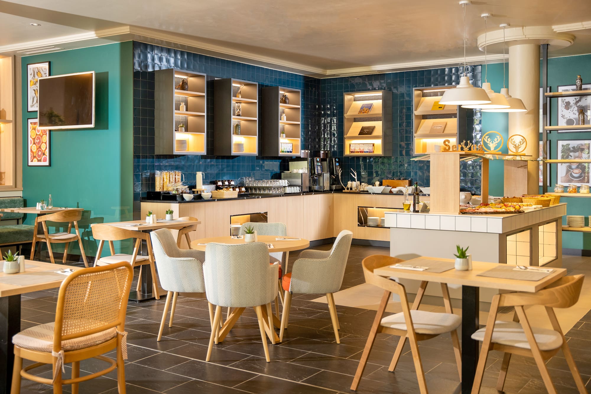 Modern hotel breakfast buffet with stylish dining tables and teal walls.