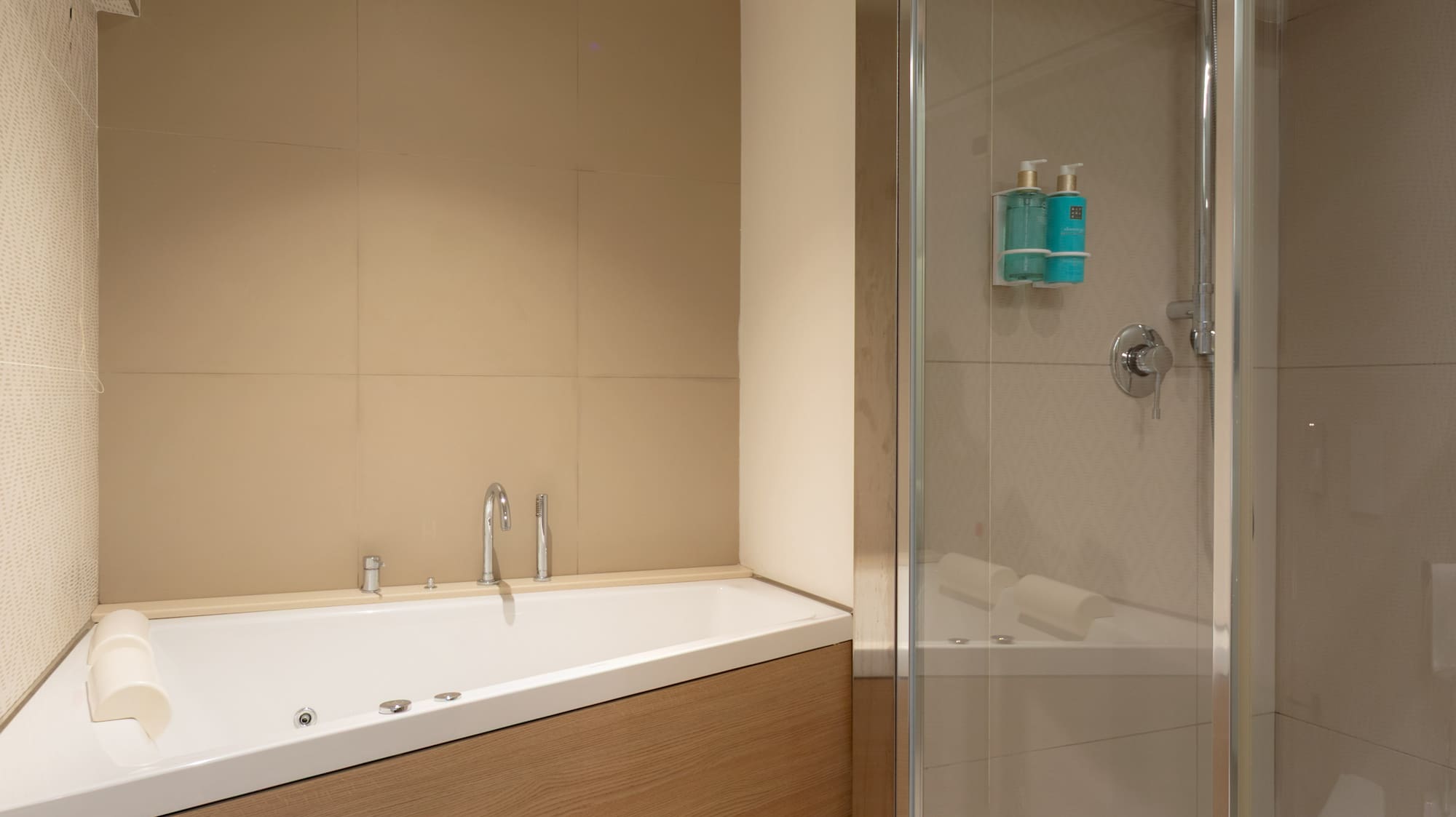 Modern bathroom with corner jacuzzi tub, wood panel, and glass shower.