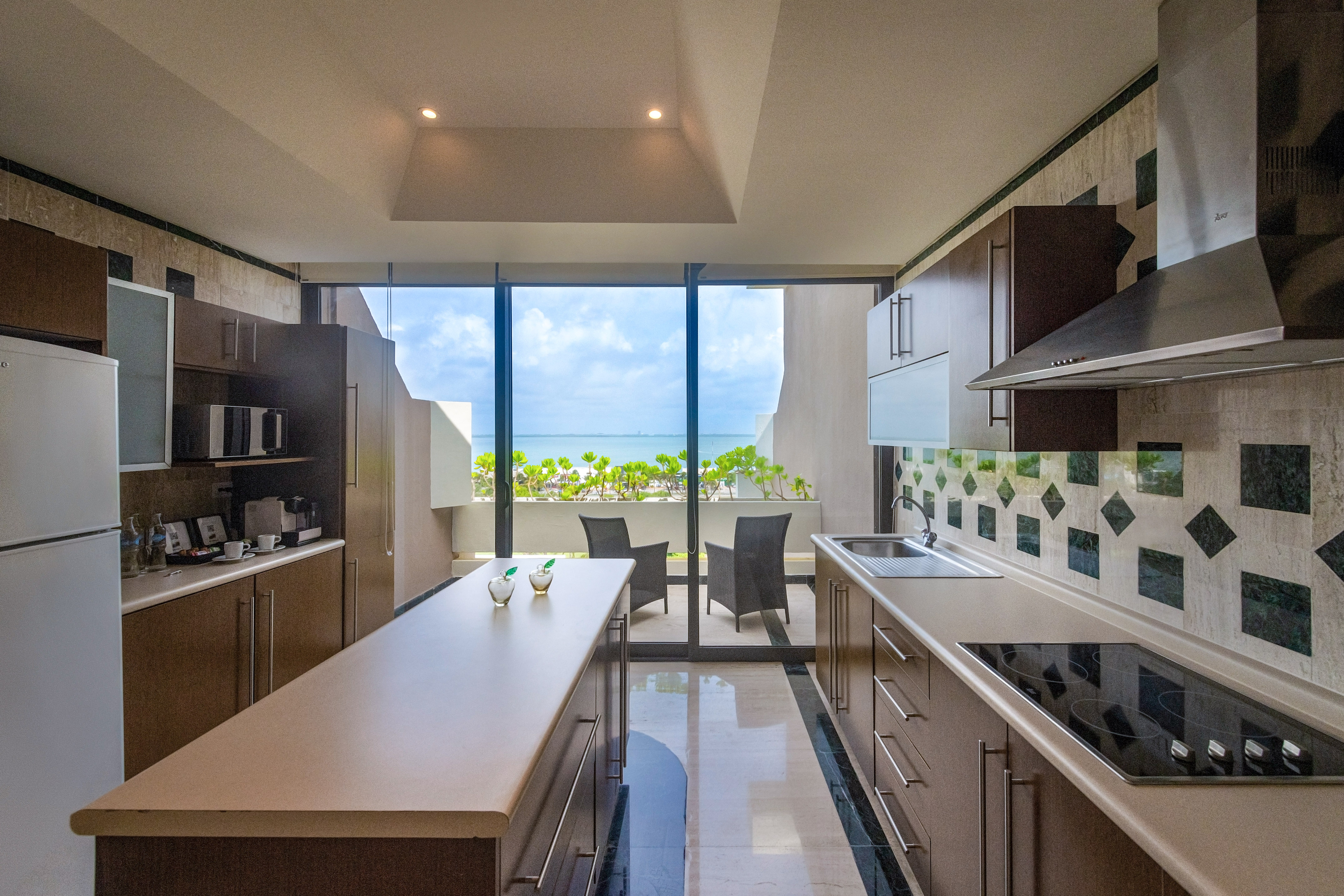 Beachfront kitchen with island, ocean view balcony, and modern appliances.