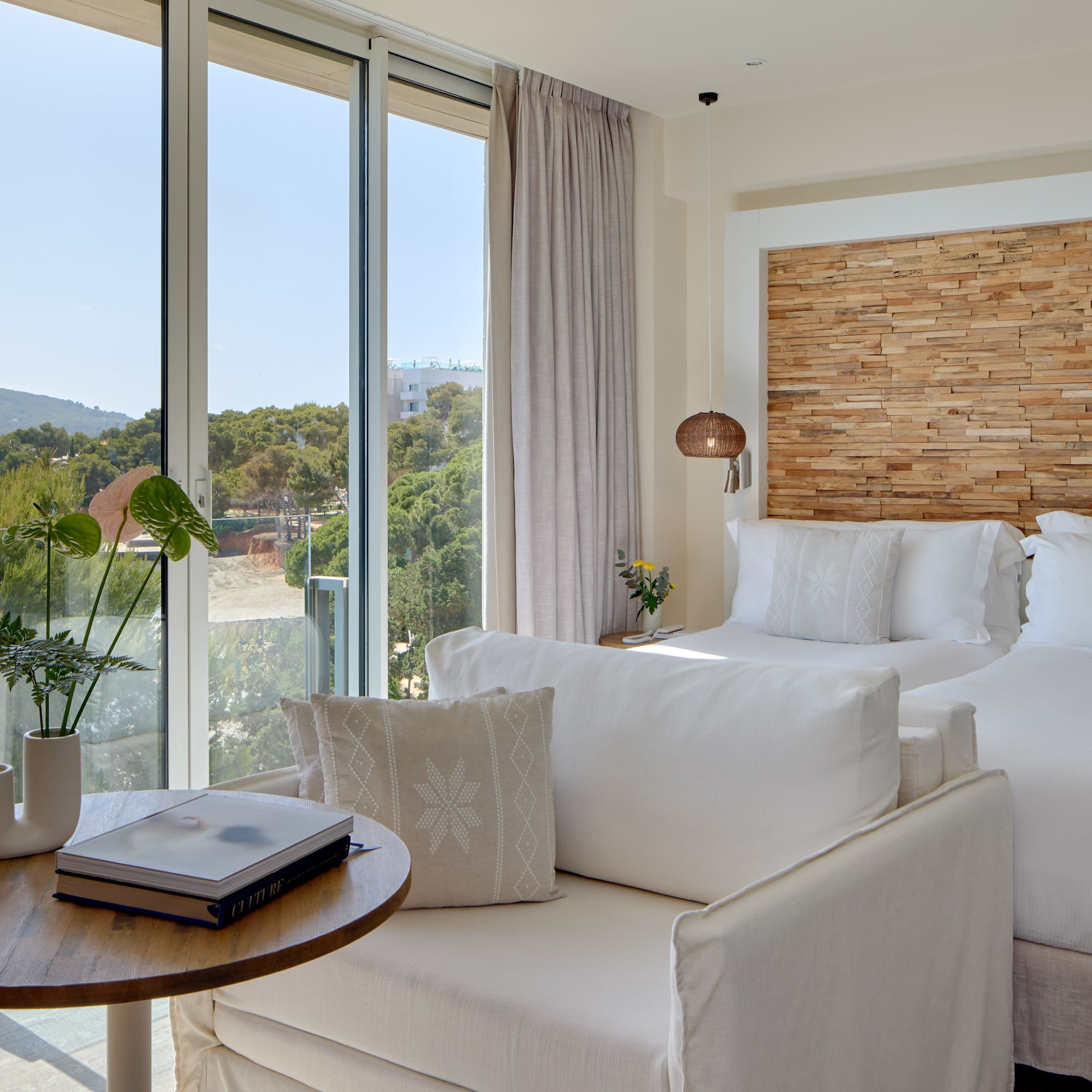 Modern coastal hotel room with sea view, two beds, and stylish wooden features.