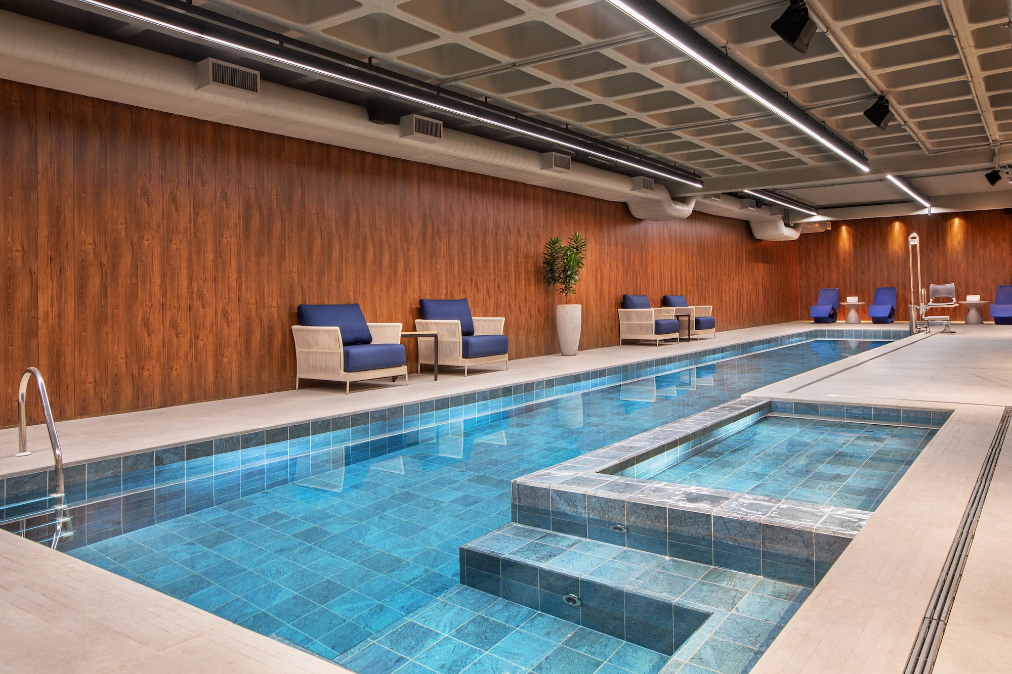 a indoor swimming pool with chairs and a bench