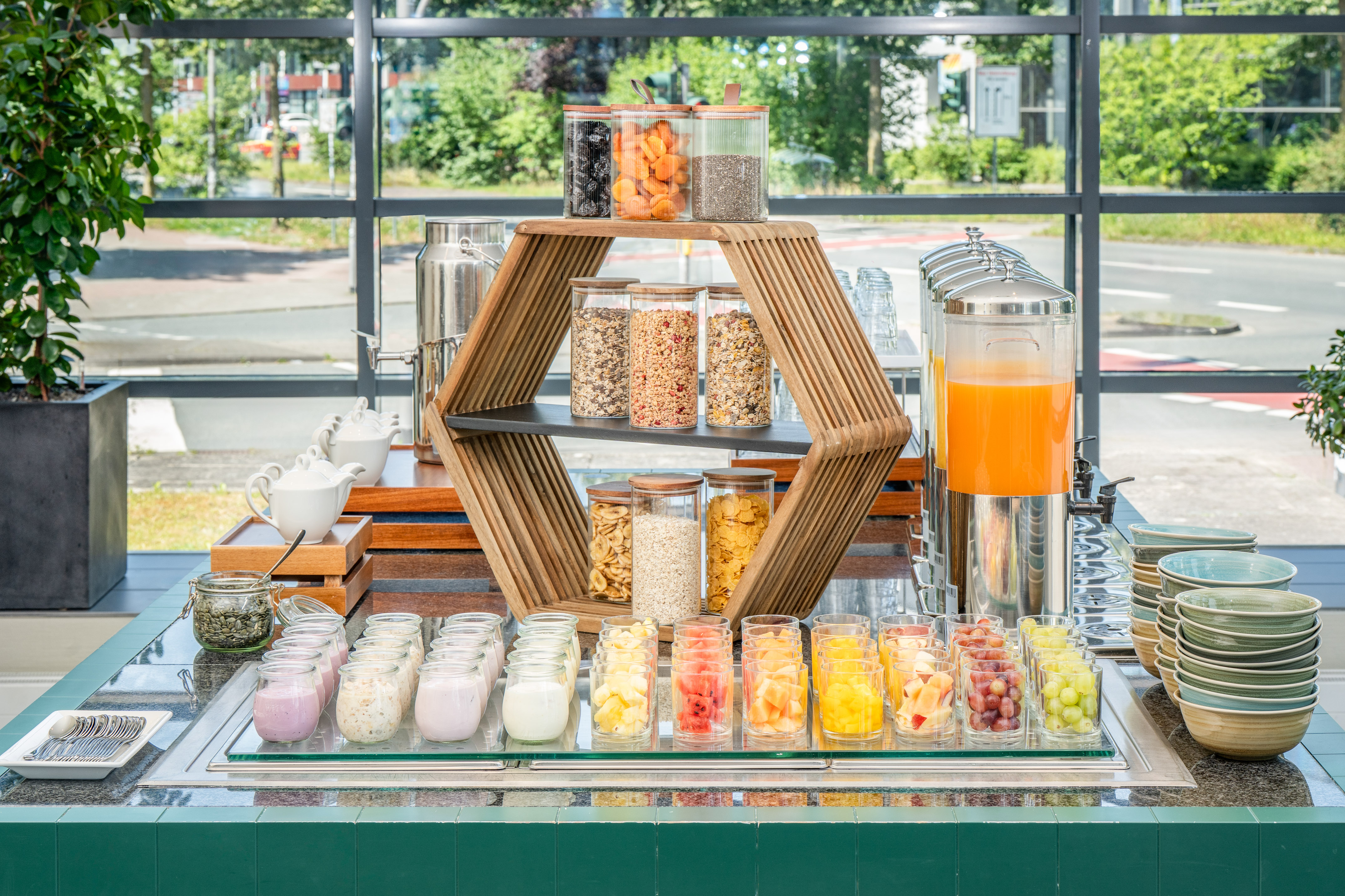 Hotel breakfast buffet with cereals, dried fruit, yogurt, fresh fruit, juice.