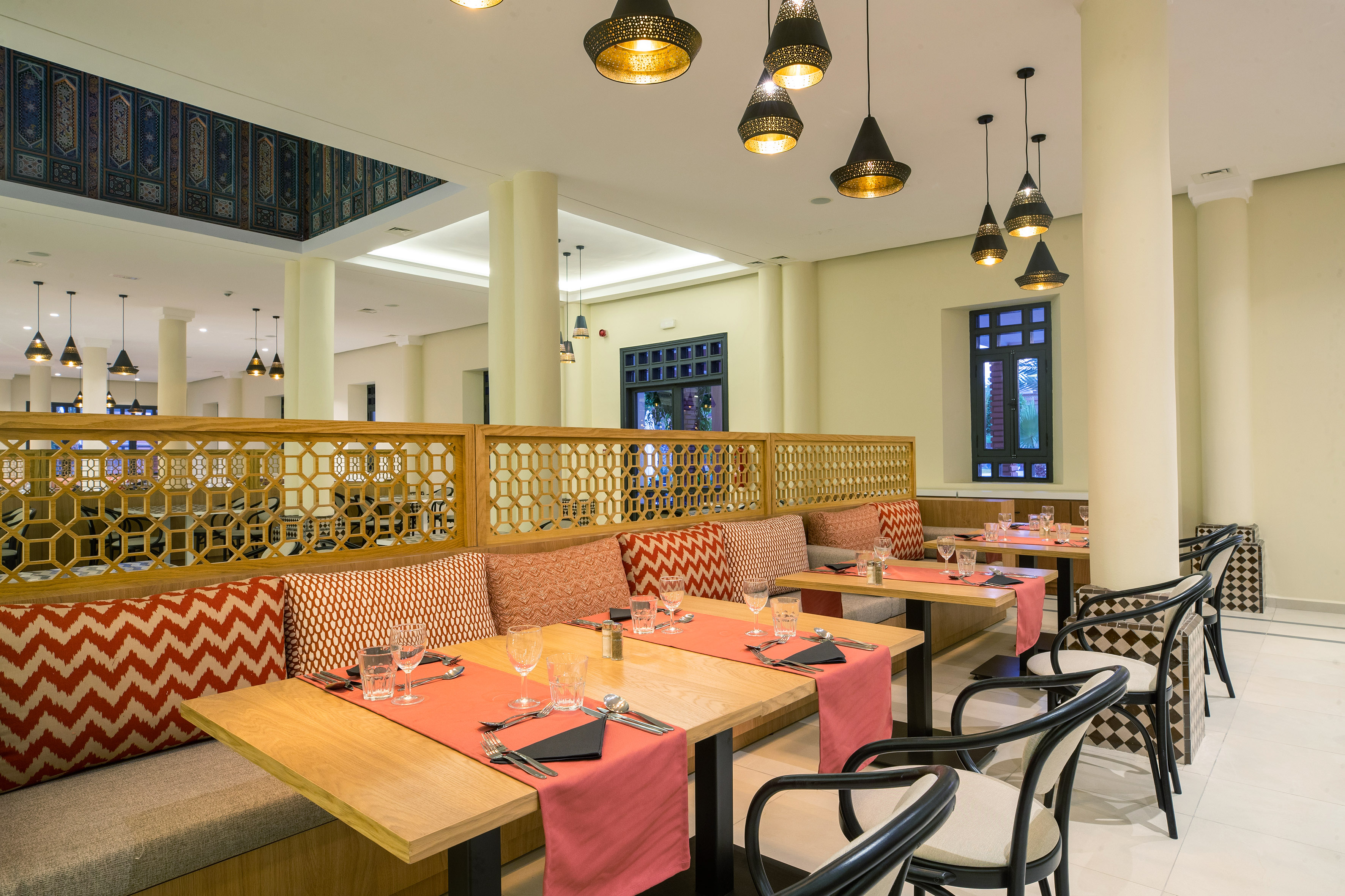 Moroccan restaurant dining with geometric screens, ornate lamps, and set tables.